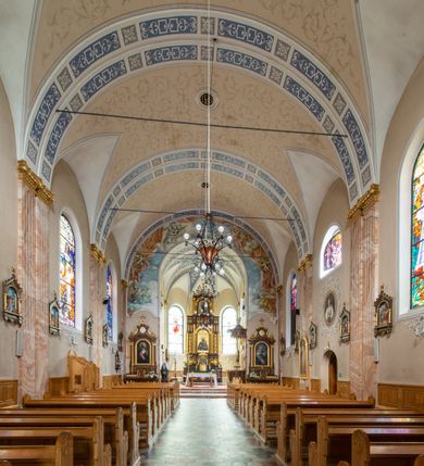 Zdjęcie nr 11: Kościół orientowany, jednonawowy, czteroprzęsłowy z niższym i węższym, jednoprzęsłowym prezbiterium zamkniętym wielobocznie. Od północnego wschodu do prezbiterium i nawy przylega zakrystia na rzucie prostokąta, od południowego wschodu prostokątna kruchta, a od zachodu kolejna prostokątna kruchta. W nawie sklepienie kolebkowe z lunetami, na zdwojonych gurtach przechodzących w pilastry o kompozytowych kapitelach i kanelowanych trzonach; w prezbiterium kolebkowe z lunetami na pojedynczych gurtach. Prezbiterium od nawy wydziela ściana tęczowa otwierająca się do wnętrza półkolistą arkadą. W ostatnim, zachodnim przęśle nawy chór muzyczny o ażurowej balustradzie, wsparty na dwóch smukłych, żeliwnych kolumnach. Otwory okienne w nawie i prezbiterium w kształcie stojącego prostokąta zamkniętego półkoliście. W ścianie zachodniej, w osi elewacji okno okrągłe. Fasada jednokondygnacyjna, jednoosiowa zamknięta trójkątną ścianą szczytową zwieńczoną krzyżem osadzonym na niewielkim daszku. W przyziemiu kruchta z otworem wejściowym w kształcie stojącego prostokąta zamkniętego łukiem półkolistym. Drzwi drewniane, dwuskrzydłowe z nadświetlem. Elewacja kruchty zamknięta schodkową ścianą szczytową zwieńczoną kamiennym krzyżem. Powyżej duże, okrągłe okno wypełnione rozetą, ujęte w motyw półkolistej arkady zaznaczonej w tynku. W górnej części fasady fryz arkadkowy. Elewacje boczne artykułowane uskokowymi przyporami, w górnej części dekorowane fryzem arkadowym. Nad nawą dach dwuspadowy, nad prezbiterium wielopołaciowy, ponad zakrystią oraz obiema kruchtami jednospadowy. Wszystkie kryte blachą. Ponad nawą umieszczona czworoboczna wieżyczka na sygnaturkę, z glorietą zwieńczoną ostrosłupowym hełmem. Na jej szczycie ażurowy krzyż. Elewacje świątyni tynkowane w odcieniach koloru żółtego oraz bieli.