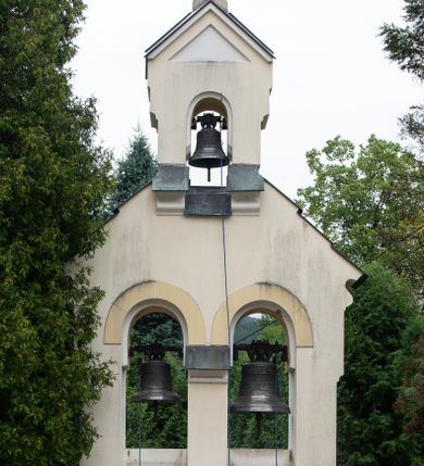 Zdjęcie nr 1: Murowana i tynkowana, wolnostojąca dzwonnica o formach architektonicznych, dwuosiowa i dwukondygnacyjna. Kondygnacja pierwsza umieszczona na niewysokim cokole, dwuosiowa, zamknięta po bokach dwuspadowym, profilowanym daszkiem krytym blachą. Elewacja z dwoma półkolistymi arkadami artykułowana wysuniętą przed jej lico lizeną zwieńczoną jednospadowym daszkiem, krytym blachą. Lica arkad zdobione dekoracją w tynku naśladującą ciosy kamienne. W prześwitach arkad zawieszone dwa dzwony. Kondygnacja druga jednoosiowa, zamknięta trójkątnym przyczółkiem z dwuspadowym daszkiem krytym blachą. W prześwicie półkolistej arkady zawieszony dzwon. W zwieńczeniu kamienny krzyż równoramienny o wklęsłej linii ramion.