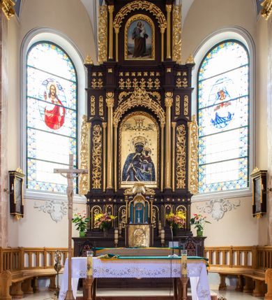Zdjęcie nr 2: Ołtarz architektoniczny, trójosiowy, dwukondygnacyjny ze zwieńczeniem, ujęty ażurowymi uszami utworzonymi z akantu oraz wstęgi regencyjnej. Mensa prostopadłościenna; antepedium drewniane z dekoracją płycinową, artykułowane pilastrami o kanelowanych trzonach. Centralna płycina w kształcie stojącego prostokąta zamkniętego od góry i dołu łukiem wyniesionym; w jej wnętrzu złocony krzyż. Tabernakulum dwukondygnacyjne, jednodrzwiczkowe z tronem wystawienia ujętym złoconymi kolumienkami dźwigającymi srebrzony baldachim w formie kopuły flankowanej akantowymi wolutami. Arkada ujmująca tron wystawienia o wykroju trójliścia, w podniebiu dekorowana złoconą muszą palmetową, poniżej której złocony monogram IHS na niebieskim tle. Drzwiczki tabernakulum złocone z umieszczonym centralnie kielichem z hostią ujętym płyciną w kształcie stojącego prostokąta zamkniętego półkoliście. Nastawa na wysokim, dwukondygnacyjnym cokole o podziałach architektonicznych. Kondygnacja druga artykułowana zwielokrotnionymi pilastrami o trzonach dekorowanych maswerkiem, pomiędzy którymi półkoliste arkadki wypełnione akantem, ujęte wąskimi, złoconymi kolumienkami. Cokół zwieńczony fryzem dekorowanym rozetkami i profilowanym gzymsem. W polu głównym ołtarza nisza w kształcie stojącego prostokąta zamkniętego łukiem półkolistym ujęta smukłymi, złoconymi kolumienkami wspierającymi bogato dekorowaną ornamentem roślinnym, kostkowaniem i rozetkami arkadę. W polu obraz przedstawiający Matkę Boską z Dzieciątkiem na złoconym tle. Oś środkowa ołtarza wyższa i szersza od bocznych, ujęta złoconymi kolumnami o korynckich kapitelach dźwigających pełne, wyłamane na osiach kolumn, belkowanie. Fryz dekorowany liśćmi akantu oraz rozetkami. Osie boczne ujęte mniejszymi, złoconymi kolumienkami, dźwigającymi półkolisty łuk. W niszach pomiędzy nimi złocona, dekoracja akantowa o pasowym przebiegu. Kondygnacja druga ujęta złoconymi kolumienkami o korynckich kapitelach oraz ażurowymi uszami utworzonymi z akantu oraz wstęgi regencyjnej, zwieńczona równoramiennym krzyżem dekorowanym rozetkami. W polu obraz w kształcie stojącego prostokąta przedstawiający św. Józefa z Dzieciątkiem Jezus. Obraz ujęty półkolistą arkadą bogato dekorowaną ornamentem roślinnym, rozetkami oraz fryzem arkadkowym, wspartą na smukłych, złoconych kolumienkach. Struktura ołtarza malowana w kolorze ciemnobrązowym, ornamentyka oraz detale elementów architektonicznych złocone.