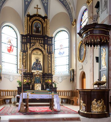 Zdjęcie nr 3: Ołtarz architektoniczny, trójosiowy, dwukondygnacyjny ze zwieńczeniem, ujęty ażurowymi uszami utworzonymi z akantu oraz wstęgi regencyjnej. Mensa prostopadłościenna; antepedium drewniane z dekoracją płycinową, artykułowane pilastrami o kanelowanych trzonach. Centralna płycina w kształcie stojącego prostokąta zamkniętego od góry i dołu łukiem wyniesionym; w jej wnętrzu złocony krzyż. Tabernakulum dwukondygnacyjne, jednodrzwiczkowe z tronem wystawienia ujętym złoconymi kolumienkami dźwigającymi srebrzony baldachim w formie kopuły flankowanej akantowymi wolutami. Arkada ujmująca tron wystawienia o wykroju trójliścia, w podniebiu dekorowana złoconą muszą palmetową, poniżej której złocony monogram IHS na niebieskim tle. Drzwiczki tabernakulum złocone z umieszczonym centralnie kielichem z hostią ujętym płyciną w kształcie stojącego prostokąta zamkniętego półkoliście. Nastawa na wysokim, dwukondygnacyjnym cokole o podziałach architektonicznych. Kondygnacja druga artykułowana zwielokrotnionymi pilastrami o trzonach dekorowanych maswerkiem, pomiędzy którymi półkoliste arkadki wypełnione akantem, ujęte wąskimi, złoconymi kolumienkami. Cokół zwieńczony fryzem dekorowanym rozetkami i profilowanym gzymsem. W polu głównym ołtarza nisza w kształcie stojącego prostokąta zamkniętego łukiem półkolistym ujęta smukłymi, złoconymi kolumienkami wspierającymi bogato dekorowaną ornamentem roślinnym, kostkowaniem i rozetkami arkadę. W polu obraz przedstawiający Matkę Boską z Dzieciątkiem na złoconym tle. Oś środkowa ołtarza wyższa i szersza od bocznych, ujęta złoconymi kolumnami o korynckich kapitelach dźwigających pełne, wyłamane na osiach kolumn, belkowanie. Fryz dekorowany liśćmi akantu oraz rozetkami. Osie boczne ujęte mniejszymi, złoconymi kolumienkami, dźwigającymi półkolisty łuk. W niszach pomiędzy nimi złocona, dekoracja akantowa o pasowym przebiegu. Kondygnacja druga ujęta złoconymi kolumienkami o korynckich kapitelach oraz ażurowymi uszami utworzonymi z akantu oraz wstęgi regencyjnej, zwieńczona równoramiennym krzyżem dekorowanym rozetkami. W polu obraz w kształcie stojącego prostokąta przedstawiający św. Józefa z Dzieciątkiem Jezus. Obraz ujęty półkolistą arkadą bogato dekorowaną ornamentem roślinnym, rozetkami oraz fryzem arkadkowym, wspartą na smukłych, złoconych kolumienkach. Struktura ołtarza malowana w kolorze ciemnobrązowym, ornamentyka oraz detale elementów architektonicznych złocone.