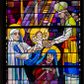 Zdjęcie nr 1: Witraż w kształcie stojącego prostokąta zamkniętego półkoliście przedstawiający Ofiarowanie Chrystusa w świątyni. Scena rozgrywa się na stopniach świątyni jerozolimskiej. Z lewej strony kompozycji ukazana Maria trzymająca na ręku Dzieciątko Jezus oraz Józef klęczący na stopniach świątyni. Maria przedstawiona w dynamicznej pozie, w wykroku, z ciałem zwróconym w trzech czwartych w lewo, ręce wyciągnięte do przodu. Ukazana jako młoda kobieta o regularnych rysach twarzy, ubrana w biało-niebieską suknię z długimi rękawami oraz chustę w tych samych kolorach zarzuconą na głowę. Na stopach ma niebieskie buty. Dzieciątko Jezus siedzące na rękach Marii przedstawione frontalnie ze stopami wyciągniętymi do przodu i rękami uniesionymi do góry. Ubrane jest w krótką, białą tunikę. Na Marię i Jezusa z prawego, górnego rogu witraża spływają wielobarwne promienie. Ponad głową Marii ukazany miecz, nad Dzieciątkiem Jezus krzyż na tle promieni. Święty Józef został przedstawiony jako dojrzały, brodaty mężczyzna ubrany w czerwono-fioletowe szaty. Na głowie ma niebieską chustę. Jest on zwrócony przodem do widza. Ręce świętego są skrzyżowane na piersi. Wokół głów wszystkich, wymienionych postaci znajdują się żółte nimby. Z prawej strony kompozycji, na najwyższym stopniu schodów przedstawiono stojących Symeona i prorokinię Annę. Symeona ukazanego z lewego profilu wyobrażono jako starszego mężczyznę z długą, siwą brodą. Zwraca się on do podawanego mu przez Marię Dzieciątka Jezus, wyciągając w jego kierunku obie ręce i pochylając głowę. Starzec ubrany jest w strój kapłański, na który składa się długa, jasna tunika oraz żółto-niebieski przewiązany w pasie pomarańczową szarfą kaftan bez rękawów i biało-żółta czapka. U bosych stóp kapłana ukazano klatkę z dwoma białymi gołębiami. Stojąca nieco z tyłu prorokini Anna została ukazana jako starsza kobieta o pomarszczonej twarzy ubrana w niebieskie szaty. Na głowie ma zarzuconą niebieską chustę.
