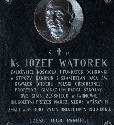 Zdjęcie nr 1: Epitafium w formie granitowej płyty o kształcie stojącego prostokąta. W górnej części, pośrodku umieszczony medalion z portretem księdza Józefa Wątorka. Zmarły przedstawiony w tzw. krótkim popiersiu z głową zwróconą w prawo. Ukazany jako dojrzały mężczyzna o okrągłej twarzy pozbawionej zarostu oraz wyraźnie zaznaczonej łysinie. Usta wąskie, nos wydatny. Charakterystyczne duże uszy. Poniżej inskrypcja
„Ś(WIĘTEJ) † P(AMIĘCI) /
Ks(iądz) JÓZEF WĄTOREK /
ZAŁOŻYCIEL KOŚCIOŁA i FUNDATOR OCHRONKI /
W STRÓŻY, KANONIK i SZAMBELAN OJCA ŚW(IĘTEGO) / 
KAWALER ORDERU „POLSKI ODRODZONEJ”. /
PROFESOR 1 GIMNAZIUM, RADCA SZKOLNY, /
DYR(EKTOR) GIMN(AZIUM) ŻEŃSKIEGO W TARNOWIE. /
DŁUGOLETNI PREZES NAUCZ(YCIELI) SZKÓŁ WYŻSZYCH. /
ZMARŁ W 66 ROKU ŻYCIA, DNIA 11 LIPCA 1930 ROKU. /
CZEŚĆ JEGO PAMIĘCI. /
WDZIĘCZNI PARAFIANIE.”
W narożach płyty umieszczone śruby o formach rozetek mocujące epitafium do ściany. 