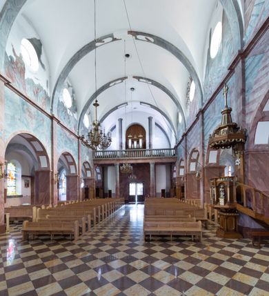 Zdjęcie nr 8: Trójnawowa, czteroprzęsłowa bazylika filarowa, z jednoprzęsłowym, zakończonym wielobocznie prezbiterium, przy którym od południa prostokątna zakrystia; od zachodu na osi wieża na rzucie kwadratu, z kruchtą w przyziemiu, częściowo wtopiona w korpus nawowy. Arkady międzynawowe i tęcza zamknięte półkoliście. Sklepienia kolebkowe z lunetami. Okna prostokątne zamknięte półkoliście, w nawie głównej, ponad arkadami międzynawowymi, okulusy. Fasada pięcioosiowa, pośrodku z ryzalitem wieży występującej przed lico elewacji nawy głównej i naw bocznych, w których zamknięte półkoliście otwory wejściowe. Wieża czterokondygnacyjna, nakryta ostrosłupowym, wysokim hełmem. Zakończenie prezbiterium opięte przyporami. Dachy dwuspadowe na nawą główną i prezbiterium, pulpitowe nad nawami bocznymi. 