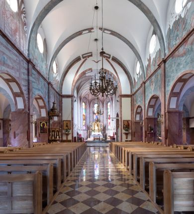 Zdjęcie nr 19: Trójnawowa, czteroprzęsłowa bazylika filarowa, z jednoprzęsłowym, zakończonym wielobocznie prezbiterium, przy którym od południa prostokątna zakrystia; od zachodu na osi wieża na rzucie kwadratu, z kruchtą w przyziemiu, częściowo wtopiona w korpus nawowy. Arkady międzynawowe i tęcza zamknięte półkoliście. Sklepienia kolebkowe z lunetami. Okna prostokątne zamknięte półkoliście, w nawie głównej, ponad arkadami międzynawowymi, okulusy. Fasada pięcioosiowa, pośrodku z ryzalitem wieży występującej przed lico elewacji nawy głównej i naw bocznych, w których zamknięte półkoliście otwory wejściowe. Wieża czterokondygnacyjna, nakryta ostrosłupowym, wysokim hełmem. Zakończenie prezbiterium opięte przyporami. Dachy dwuspadowe na nawą główną i prezbiterium, pulpitowe nad nawami bocznymi. 