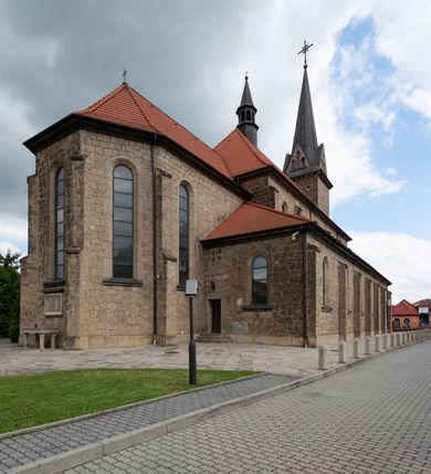 Zdjęcie nr 18: Trójnawowa, czteroprzęsłowa bazylika filarowa, z jednoprzęsłowym, zakończonym wielobocznie prezbiterium, przy którym od południa prostokątna zakrystia; od zachodu na osi wieża na rzucie kwadratu, z kruchtą w przyziemiu, częściowo wtopiona w korpus nawowy. Arkady międzynawowe i tęcza zamknięte półkoliście. Sklepienia kolebkowe z lunetami. Okna prostokątne zamknięte półkoliście, w nawie głównej, ponad arkadami międzynawowymi, okulusy. Fasada pięcioosiowa, pośrodku z ryzalitem wieży występującej przed lico elewacji nawy głównej i naw bocznych, w których zamknięte półkoliście otwory wejściowe. Wieża czterokondygnacyjna, nakryta ostrosłupowym, wysokim hełmem. Zakończenie prezbiterium opięte przyporami. Dachy dwuspadowe na nawą główną i prezbiterium, pulpitowe nad nawami bocznymi. 