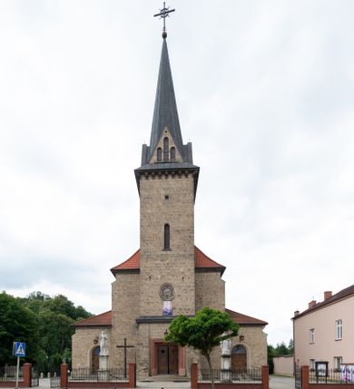 Zdjęcie nr 1: Trójnawowa, czteroprzęsłowa bazylika filarowa, z jednoprzęsłowym, zakończonym wielobocznie prezbiterium, przy którym od południa prostokątna zakrystia; od zachodu na osi wieża na rzucie kwadratu, z kruchtą w przyziemiu, częściowo wtopiona w korpus nawowy. Arkady międzynawowe i tęcza zamknięte półkoliście. Sklepienia kolebkowe z lunetami. Okna prostokątne zamknięte półkoliście, w nawie głównej, ponad arkadami międzynawowymi, okulusy. Fasada pięcioosiowa, pośrodku z ryzalitem wieży występującej przed lico elewacji nawy głównej i naw bocznych, w których zamknięte półkoliście otwory wejściowe. Wieża czterokondygnacyjna, nakryta ostrosłupowym, wysokim hełmem. Zakończenie prezbiterium opięte przyporami. Dachy dwuspadowe na nawą główną i prezbiterium, pulpitowe nad nawami bocznymi. 