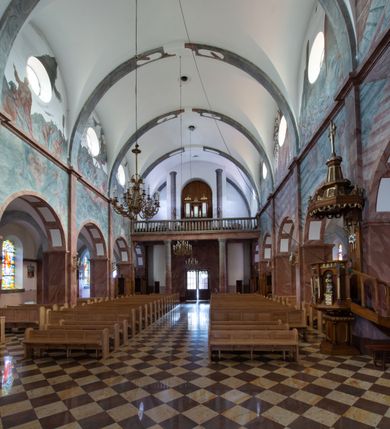 Zdjęcie nr 14: Trójnawowa, czteroprzęsłowa bazylika filarowa, z jednoprzęsłowym, zakończonym wielobocznie prezbiterium, przy którym od południa prostokątna zakrystia; od zachodu na osi wieża na rzucie kwadratu, z kruchtą w przyziemiu, częściowo wtopiona w korpus nawowy. Arkady międzynawowe i tęcza zamknięte półkoliście. Sklepienia kolebkowe z lunetami. Okna prostokątne zamknięte półkoliście, w nawie głównej, ponad arkadami międzynawowymi, okulusy. Fasada pięcioosiowa, pośrodku z ryzalitem wieży występującej przed lico elewacji nawy głównej i naw bocznych, w których zamknięte półkoliście otwory wejściowe. Wieża czterokondygnacyjna, nakryta ostrosłupowym, wysokim hełmem. Zakończenie prezbiterium opięte przyporami. Dachy dwuspadowe na nawą główną i prezbiterium, pulpitowe nad nawami bocznymi. 