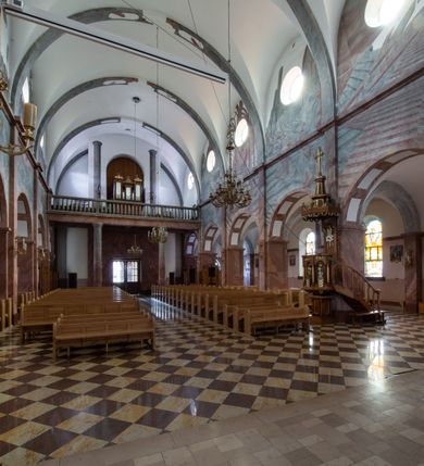 Zdjęcie nr 15: Trójnawowa, czteroprzęsłowa bazylika filarowa, z jednoprzęsłowym, zakończonym wielobocznie prezbiterium, przy którym od południa prostokątna zakrystia; od zachodu na osi wieża na rzucie kwadratu, z kruchtą w przyziemiu, częściowo wtopiona w korpus nawowy. Arkady międzynawowe i tęcza zamknięte półkoliście. Sklepienia kolebkowe z lunetami. Okna prostokątne zamknięte półkoliście, w nawie głównej, ponad arkadami międzynawowymi, okulusy. Fasada pięcioosiowa, pośrodku z ryzalitem wieży występującej przed lico elewacji nawy głównej i naw bocznych, w których zamknięte półkoliście otwory wejściowe. Wieża czterokondygnacyjna, nakryta ostrosłupowym, wysokim hełmem. Zakończenie prezbiterium opięte przyporami. Dachy dwuspadowe na nawą główną i prezbiterium, pulpitowe nad nawami bocznymi. 