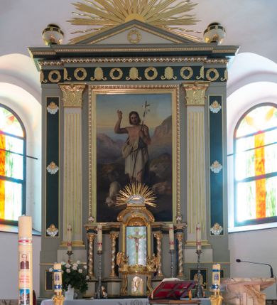 Zdjęcie nr 1: Ołtarz architektoniczny, przyścienny, jednokondygnacyjny, jednoosiowy, w formie aediculi. Mensa prostopadłościenna, na niej tabernakulum w formie zbliżonej do prostopadłościennej skrzynki o wypukłej ściance frontowej ustawione na tle ścianki z tronem wystawienia ujętym ramką zamkniętą łukiem nadwieszonym. Drzwiczki tabernakulum dekorowane kielichem z hostią, ujęte wolutami. Tron wystawienia oraz ściankę flankują kręcone kolumny podtrzymujące wyłamane na ich osiach belkowanie. Niszę wypełnia pasyjka na tle kół dekorowanych liliami, po jej dwóch stronach klęczące anioły trzymające kielichy. Tabernakulum polichromowane na kolor jasnoszary, fryz ciemnoszary, profile złocone.
Nastawa na wysokim cokole dekorowanym prostokątnymi płycinami z dekoracją. W polu głównym rama w kształcie stojącego prostokąta, a w niej obraz z przedstawieniem św. Jana Chrzciciela. Pole flankowane zakończonymi kapitelami, kanelowanymi pilastrami podtrzymującymi wyłamane nad polem centralnym belkowanie. Na osiach zewnętrznych prostokątne płyciny. Całość zwieńczona trójkątnym przyczółkiem  z polem wypełnionym wieńcem i glorią promienistą z wiązkami prostych promieni przedzielonymi pojedynczymi, falistymi. Na skrajnych fragmentach belkowania wazony. 
Na zewnętrznych płycinach uskrzydlone aniołki na chmurach, fryz z dekoracją z naprzemiennie umieszczonych wieńców i palmet poniżej perełkowania, krawędzie zwieńczenia podkreślone rzędami listków. 
Struktura w kolorze jasnoszarym, płyciny ciemnoszare, profile, ornamenty i dekoracje złocone i srebrzone.
