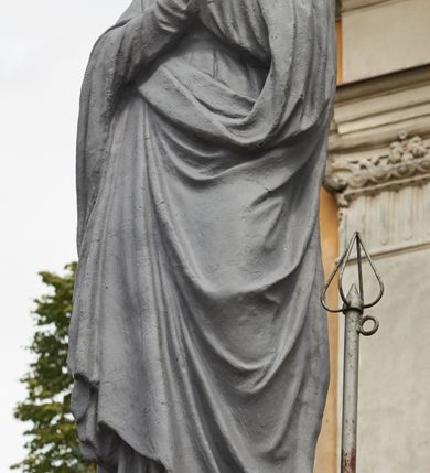 Zdjęcie nr 30: Kościół jest orientowany, murowany z cegły i kamienia, na rzucie podłużnym. Zajmuje powierzchnię około 606 metrów kwadratowych, długość bryły wynosi około 32, a szerokość 14 metrów. Jednonawowy, trójprzęsłowy korpus charakteryzuje środkowe, kwadratowe przęsło z płytkimi apsydami po bokach, wysuwającymi się przed lica elewacji bocznych, na wzór pseudotranseptu (para spłaszczonych apsyd). Przęsło wschodnie, na rzucie prostokąta, z wnękami po bokach, zakończone jest apsydą stanowiącą przestrzeń prezbiterium. Na osi kościoła i przedłużeniu prezbiterium jest piętrowa zakrystia ze skarbcem, natomiast w przedłużeniu przęsła zachodniego wieża ujęta po bokach piętrowymi lokalnościami. Korpus nawowy przekryty jest sklepieniem kolebkowym na gurtach, z lunetami, które w przęśle środkowym, na przecięciu z pseudotranseptem, tworzy rodzaj sklepienia krzyżowego z okrągłym zwierciadłem. Artykulację ścian wewnątrz kościoła stanowią pary pilastrów wspierające przerywane belkowanie. Na zewnątrz ściany korpusu, transeptu i zakrystii artykułują osadzone na niewysokim cokole lizeny wspierające obiegające całość belkowanie. Dodatkowo mury przeprute są owalnymi otworami okiennymi ujętymi profilowanymi obramieniami. Fasadę charakteryzuje w części środkowej ryzalit o skośnych ściankach bocznych oraz podziały podwójnymi i pojedynczymi pilastrami jońskimi, osadzonymi na wysokich cokołach i wspierającymi belkowanie. Do wnętrza kościoła prowadzą trzy otwory drzwiowe – w elewacji południowej, północnej i zachodniej. Drzwi w fasadzie są ujęte dekoracyjnym portalem z parą wąskich pilastrów, zwieńczonych zwężającymi się ku dołowi kapitelami, wspierających gzyms w formie łuku odcinkowego. Całość ujmuje obramienie o fantazyjnym wykroju w górnej partii, którego krawędzie obiega profilowana listwa z parą niewielkich wolut w górnych narożach. Obramienie drzwi wieńczy prosty gzyms odcinkowy nakryty blaszanym daszkiem. Po bokach wejścia znajduje się para kamiennych kropielnic. Powyżej otworu drzwiowego, pole środkowe fasady przeprute zostało oknem w kształcie stojącego prostokąta zamkniętego łukiem odcinkowym, zamurowanego w jednej trzeciej wysokości. Obramienie okna jest w formie pary pilastrów bez baz, wspierających fryz z kluczem pośrodku i parą wsporników wolutowych po bokach, dźwigających odcinkowy gzyms wieńczący. Pod parapetem umieszczono fartuch w kształcie leżącego prostokąta, o wklęsłych dolnych narożach, z dolną krawędzią zdobioną motywem lambrekinu. W skośnych ścianach bocznych ryzalitu znajduje się para zamkniętych półkoliście niszy z figurami św. Piotra po lewej i św. Pawła po prawej stronie. 
Ryzalit wieńczy trójkątny przyczółek z herbem Nowina w tympanonie. Nad belkowaniem, na całej szerokości fasady, znajduje się prosta attyka z odpowiadającymi dolnej strefie elewacji podziałami lizenowymi, wspierającymi wyłamujący się ponad nimi gzyms ozdobiony wazonami. Powyżej wznosi się górne piętro wieży, czworościenne o ściętych narożnikach, nakryte kopulastym hełmem z nasadnikiem.  
Północna, zachodnia i południowa ściana wieży przeprute są otworami okiennymi w kształcie stojącego prostokąta zamkniętego łukiem odcinkowym. Okna mają obramienia w kształcie stojących prostokątów z uszakami w górnych narożach, zwieńczone są belkowaniem w formie łuku odcinkowego z kluczem pośrodku i parą wolutowych wsporników po bokach fryzu. Podwieszenie ma formę fartucha w kształcie leżącego prostokąta o wklęsłych dolnych narożach i dolnej krawędzi zdobionej motywem lambrekinu. Powyżej otworów okiennych znajdują się okrągłe tarcze zegarowe. Pola ściętych naroży wieży zdobi ornamentyka cekinowa i kampanule. Korpus nawowy przykrywa dwuspadowy dach zakończony pięciopołaciowo nad prezbiterium i trójpołaciowo nad końcami transeptu, kryty dachówką. Na skrzyżowaniu korpusu nawowego i transeptu ulokowano obitą blachą wieżyczkę na sygnaturkę. Kolorystyka tynków kościoła utrzymana jest w odcieniu ugru, w dolnej partii różu, detal architektoniczny i ornamentyka w bieli. 

Plac przykościelny otoczony jest murowanym parkanem z usytuowanymi w nim 14 kapliczkami ze stacjami drogi krzyżowej, nakrytymi dwuspadowymi dachami. W jednym z naroży znajduje się niewielka, murowana kaplica grobowa rodziny Romerów o ceglanych ścianach artykułowanych białymi pilastrami i fasadzie ze szczytem ujętym parą spływów i zwieńczonym trójkątnym przyczółkiem.   
