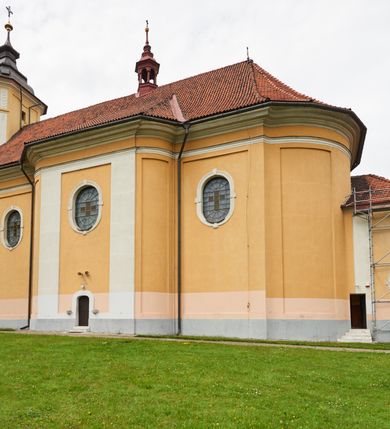 Zdjęcie nr 23: Kościół jest orientowany, murowany z cegły i kamienia, na rzucie podłużnym. Zajmuje powierzchnię około 606 metrów kwadratowych, długość bryły wynosi około 32, a szerokość 14 metrów. Jednonawowy, trójprzęsłowy korpus charakteryzuje środkowe, kwadratowe przęsło z płytkimi apsydami po bokach, wysuwającymi się przed lica elewacji bocznych, na wzór pseudotranseptu (para spłaszczonych apsyd). Przęsło wschodnie, na rzucie prostokąta, z wnękami po bokach, zakończone jest apsydą stanowiącą przestrzeń prezbiterium. Na osi kościoła i przedłużeniu prezbiterium jest piętrowa zakrystia ze skarbcem, natomiast w przedłużeniu przęsła zachodniego wieża ujęta po bokach piętrowymi lokalnościami. Korpus nawowy przekryty jest sklepieniem kolebkowym na gurtach, z lunetami, które w przęśle środkowym, na przecięciu z pseudotranseptem, tworzy rodzaj sklepienia krzyżowego z okrągłym zwierciadłem. Artykulację ścian wewnątrz kościoła stanowią pary pilastrów wspierające przerywane belkowanie. Na zewnątrz ściany korpusu, transeptu i zakrystii artykułują osadzone na niewysokim cokole lizeny wspierające obiegające całość belkowanie. Dodatkowo mury przeprute są owalnymi otworami okiennymi ujętymi profilowanymi obramieniami. Fasadę charakteryzuje w części środkowej ryzalit o skośnych ściankach bocznych oraz podziały podwójnymi i pojedynczymi pilastrami jońskimi, osadzonymi na wysokich cokołach i wspierającymi belkowanie. Do wnętrza kościoła prowadzą trzy otwory drzwiowe – w elewacji południowej, północnej i zachodniej. Drzwi w fasadzie są ujęte dekoracyjnym portalem z parą wąskich pilastrów, zwieńczonych zwężającymi się ku dołowi kapitelami, wspierających gzyms w formie łuku odcinkowego. Całość ujmuje obramienie o fantazyjnym wykroju w górnej partii, którego krawędzie obiega profilowana listwa z parą niewielkich wolut w górnych narożach. Obramienie drzwi wieńczy prosty gzyms odcinkowy nakryty blaszanym daszkiem. Po bokach wejścia znajduje się para kamiennych kropielnic. Powyżej otworu drzwiowego, pole środkowe fasady przeprute zostało oknem w kształcie stojącego prostokąta zamkniętego łukiem odcinkowym, zamurowanego w jednej trzeciej wysokości. Obramienie okna jest w formie pary pilastrów bez baz, wspierających fryz z kluczem pośrodku i parą wsporników wolutowych po bokach, dźwigających odcinkowy gzyms wieńczący. Pod parapetem umieszczono fartuch w kształcie leżącego prostokąta, o wklęsłych dolnych narożach, z dolną krawędzią zdobioną motywem lambrekinu. W skośnych ścianach bocznych ryzalitu znajduje się para zamkniętych półkoliście niszy z figurami św. Piotra po lewej i św. Pawła po prawej stronie. 
Ryzalit wieńczy trójkątny przyczółek z herbem Nowina w tympanonie. Nad belkowaniem, na całej szerokości fasady, znajduje się prosta attyka z odpowiadającymi dolnej strefie elewacji podziałami lizenowymi, wspierającymi wyłamujący się ponad nimi gzyms ozdobiony wazonami. Powyżej wznosi się górne piętro wieży, czworościenne o ściętych narożnikach, nakryte kopulastym hełmem z nasadnikiem.  
Północna, zachodnia i południowa ściana wieży przeprute są otworami okiennymi w kształcie stojącego prostokąta zamkniętego łukiem odcinkowym. Okna mają obramienia w kształcie stojących prostokątów z uszakami w górnych narożach, zwieńczone są belkowaniem w formie łuku odcinkowego z kluczem pośrodku i parą wolutowych wsporników po bokach fryzu. Podwieszenie ma formę fartucha w kształcie leżącego prostokąta o wklęsłych dolnych narożach i dolnej krawędzi zdobionej motywem lambrekinu. Powyżej otworów okiennych znajdują się okrągłe tarcze zegarowe. Pola ściętych naroży wieży zdobi ornamentyka cekinowa i kampanule. Korpus nawowy przykrywa dwuspadowy dach zakończony pięciopołaciowo nad prezbiterium i trójpołaciowo nad końcami transeptu, kryty dachówką. Na skrzyżowaniu korpusu nawowego i transeptu ulokowano obitą blachą wieżyczkę na sygnaturkę. Kolorystyka tynków kościoła utrzymana jest w odcieniu ugru, w dolnej partii różu, detal architektoniczny i ornamentyka w bieli. 

Plac przykościelny otoczony jest murowanym parkanem z usytuowanymi w nim 14 kapliczkami ze stacjami drogi krzyżowej, nakrytymi dwuspadowymi dachami. W jednym z naroży znajduje się niewielka, murowana kaplica grobowa rodziny Romerów o ceglanych ścianach artykułowanych białymi pilastrami i fasadzie ze szczytem ujętym parą spływów i zwieńczonym trójkątnym przyczółkiem.   
