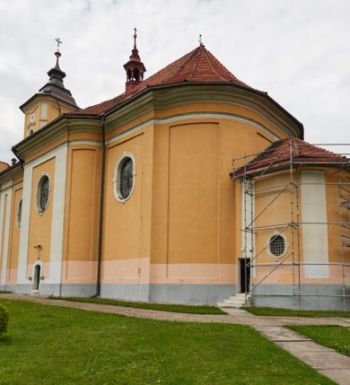 Zdjęcie nr 24: Kościół jest orientowany, murowany z cegły i kamienia, na rzucie podłużnym. Zajmuje powierzchnię około 606 metrów kwadratowych, długość bryły wynosi około 32, a szerokość 14 metrów. Jednonawowy, trójprzęsłowy korpus charakteryzuje środkowe, kwadratowe przęsło z płytkimi apsydami po bokach, wysuwającymi się przed lica elewacji bocznych, na wzór pseudotranseptu (para spłaszczonych apsyd). Przęsło wschodnie, na rzucie prostokąta, z wnękami po bokach, zakończone jest apsydą stanowiącą przestrzeń prezbiterium. Na osi kościoła i przedłużeniu prezbiterium jest piętrowa zakrystia ze skarbcem, natomiast w przedłużeniu przęsła zachodniego wieża ujęta po bokach piętrowymi lokalnościami. Korpus nawowy przekryty jest sklepieniem kolebkowym na gurtach, z lunetami, które w przęśle środkowym, na przecięciu z pseudotranseptem, tworzy rodzaj sklepienia krzyżowego z okrągłym zwierciadłem. Artykulację ścian wewnątrz kościoła stanowią pary pilastrów wspierające przerywane belkowanie. Na zewnątrz ściany korpusu, transeptu i zakrystii artykułują osadzone na niewysokim cokole lizeny wspierające obiegające całość belkowanie. Dodatkowo mury przeprute są owalnymi otworami okiennymi ujętymi profilowanymi obramieniami. Fasadę charakteryzuje w części środkowej ryzalit o skośnych ściankach bocznych oraz podziały podwójnymi i pojedynczymi pilastrami jońskimi, osadzonymi na wysokich cokołach i wspierającymi belkowanie. Do wnętrza kościoła prowadzą trzy otwory drzwiowe – w elewacji południowej, północnej i zachodniej. Drzwi w fasadzie są ujęte dekoracyjnym portalem z parą wąskich pilastrów, zwieńczonych zwężającymi się ku dołowi kapitelami, wspierających gzyms w formie łuku odcinkowego. Całość ujmuje obramienie o fantazyjnym wykroju w górnej partii, którego krawędzie obiega profilowana listwa z parą niewielkich wolut w górnych narożach. Obramienie drzwi wieńczy prosty gzyms odcinkowy nakryty blaszanym daszkiem. Po bokach wejścia znajduje się para kamiennych kropielnic. Powyżej otworu drzwiowego, pole środkowe fasady przeprute zostało oknem w kształcie stojącego prostokąta zamkniętego łukiem odcinkowym, zamurowanego w jednej trzeciej wysokości. Obramienie okna jest w formie pary pilastrów bez baz, wspierających fryz z kluczem pośrodku i parą wsporników wolutowych po bokach, dźwigających odcinkowy gzyms wieńczący. Pod parapetem umieszczono fartuch w kształcie leżącego prostokąta, o wklęsłych dolnych narożach, z dolną krawędzią zdobioną motywem lambrekinu. W skośnych ścianach bocznych ryzalitu znajduje się para zamkniętych półkoliście niszy z figurami św. Piotra po lewej i św. Pawła po prawej stronie. 
Ryzalit wieńczy trójkątny przyczółek z herbem Nowina w tympanonie. Nad belkowaniem, na całej szerokości fasady, znajduje się prosta attyka z odpowiadającymi dolnej strefie elewacji podziałami lizenowymi, wspierającymi wyłamujący się ponad nimi gzyms ozdobiony wazonami. Powyżej wznosi się górne piętro wieży, czworościenne o ściętych narożnikach, nakryte kopulastym hełmem z nasadnikiem.  
Północna, zachodnia i południowa ściana wieży przeprute są otworami okiennymi w kształcie stojącego prostokąta zamkniętego łukiem odcinkowym. Okna mają obramienia w kształcie stojących prostokątów z uszakami w górnych narożach, zwieńczone są belkowaniem w formie łuku odcinkowego z kluczem pośrodku i parą wolutowych wsporników po bokach fryzu. Podwieszenie ma formę fartucha w kształcie leżącego prostokąta o wklęsłych dolnych narożach i dolnej krawędzi zdobionej motywem lambrekinu. Powyżej otworów okiennych znajdują się okrągłe tarcze zegarowe. Pola ściętych naroży wieży zdobi ornamentyka cekinowa i kampanule. Korpus nawowy przykrywa dwuspadowy dach zakończony pięciopołaciowo nad prezbiterium i trójpołaciowo nad końcami transeptu, kryty dachówką. Na skrzyżowaniu korpusu nawowego i transeptu ulokowano obitą blachą wieżyczkę na sygnaturkę. Kolorystyka tynków kościoła utrzymana jest w odcieniu ugru, w dolnej partii różu, detal architektoniczny i ornamentyka w bieli. 

Plac przykościelny otoczony jest murowanym parkanem z usytuowanymi w nim 14 kapliczkami ze stacjami drogi krzyżowej, nakrytymi dwuspadowymi dachami. W jednym z naroży znajduje się niewielka, murowana kaplica grobowa rodziny Romerów o ceglanych ścianach artykułowanych białymi pilastrami i fasadzie ze szczytem ujętym parą spływów i zwieńczonym trójkątnym przyczółkiem.   
