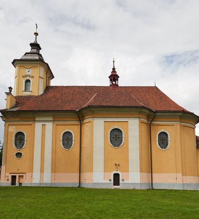 Zdjęcie nr 18: Kościół jest orientowany, murowany z cegły i kamienia, na rzucie podłużnym. Zajmuje powierzchnię około 606 metrów kwadratowych, długość bryły wynosi około 32, a szerokość 14 metrów. Jednonawowy, trójprzęsłowy korpus charakteryzuje środkowe, kwadratowe przęsło z płytkimi apsydami po bokach, wysuwającymi się przed lica elewacji bocznych, na wzór pseudotranseptu (para spłaszczonych apsyd). Przęsło wschodnie, na rzucie prostokąta, z wnękami po bokach, zakończone jest apsydą stanowiącą przestrzeń prezbiterium. Na osi kościoła i przedłużeniu prezbiterium jest piętrowa zakrystia ze skarbcem, natomiast w przedłużeniu przęsła zachodniego wieża ujęta po bokach piętrowymi lokalnościami. Korpus nawowy przekryty jest sklepieniem kolebkowym na gurtach, z lunetami, które w przęśle środkowym, na przecięciu z pseudotranseptem, tworzy rodzaj sklepienia krzyżowego z okrągłym zwierciadłem. Artykulację ścian wewnątrz kościoła stanowią pary pilastrów wspierające przerywane belkowanie. Na zewnątrz ściany korpusu, transeptu i zakrystii artykułują osadzone na niewysokim cokole lizeny wspierające obiegające całość belkowanie. Dodatkowo mury przeprute są owalnymi otworami okiennymi ujętymi profilowanymi obramieniami. Fasadę charakteryzuje w części środkowej ryzalit o skośnych ściankach bocznych oraz podziały podwójnymi i pojedynczymi pilastrami jońskimi, osadzonymi na wysokich cokołach i wspierającymi belkowanie. Do wnętrza kościoła prowadzą trzy otwory drzwiowe – w elewacji południowej, północnej i zachodniej. Drzwi w fasadzie są ujęte dekoracyjnym portalem z parą wąskich pilastrów, zwieńczonych zwężającymi się ku dołowi kapitelami, wspierających gzyms w formie łuku odcinkowego. Całość ujmuje obramienie o fantazyjnym wykroju w górnej partii, którego krawędzie obiega profilowana listwa z parą niewielkich wolut w górnych narożach. Obramienie drzwi wieńczy prosty gzyms odcinkowy nakryty blaszanym daszkiem. Po bokach wejścia znajduje się para kamiennych kropielnic. Powyżej otworu drzwiowego, pole środkowe fasady przeprute zostało oknem w kształcie stojącego prostokąta zamkniętego łukiem odcinkowym, zamurowanego w jednej trzeciej wysokości. Obramienie okna jest w formie pary pilastrów bez baz, wspierających fryz z kluczem pośrodku i parą wsporników wolutowych po bokach, dźwigających odcinkowy gzyms wieńczący. Pod parapetem umieszczono fartuch w kształcie leżącego prostokąta, o wklęsłych dolnych narożach, z dolną krawędzią zdobioną motywem lambrekinu. W skośnych ścianach bocznych ryzalitu znajduje się para zamkniętych półkoliście niszy z figurami św. Piotra po lewej i św. Pawła po prawej stronie. 
Ryzalit wieńczy trójkątny przyczółek z herbem Nowina w tympanonie. Nad belkowaniem, na całej szerokości fasady, znajduje się prosta attyka z odpowiadającymi dolnej strefie elewacji podziałami lizenowymi, wspierającymi wyłamujący się ponad nimi gzyms ozdobiony wazonami. Powyżej wznosi się górne piętro wieży, czworościenne o ściętych narożnikach, nakryte kopulastym hełmem z nasadnikiem.  
Północna, zachodnia i południowa ściana wieży przeprute są otworami okiennymi w kształcie stojącego prostokąta zamkniętego łukiem odcinkowym. Okna mają obramienia w kształcie stojących prostokątów z uszakami w górnych narożach, zwieńczone są belkowaniem w formie łuku odcinkowego z kluczem pośrodku i parą wolutowych wsporników po bokach fryzu. Podwieszenie ma formę fartucha w kształcie leżącego prostokąta o wklęsłych dolnych narożach i dolnej krawędzi zdobionej motywem lambrekinu. Powyżej otworów okiennych znajdują się okrągłe tarcze zegarowe. Pola ściętych naroży wieży zdobi ornamentyka cekinowa i kampanule. Korpus nawowy przykrywa dwuspadowy dach zakończony pięciopołaciowo nad prezbiterium i trójpołaciowo nad końcami transeptu, kryty dachówką. Na skrzyżowaniu korpusu nawowego i transeptu ulokowano obitą blachą wieżyczkę na sygnaturkę. Kolorystyka tynków kościoła utrzymana jest w odcieniu ugru, w dolnej partii różu, detal architektoniczny i ornamentyka w bieli. 

Plac przykościelny otoczony jest murowanym parkanem z usytuowanymi w nim 14 kapliczkami ze stacjami drogi krzyżowej, nakrytymi dwuspadowymi dachami. W jednym z naroży znajduje się niewielka, murowana kaplica grobowa rodziny Romerów o ceglanych ścianach artykułowanych białymi pilastrami i fasadzie ze szczytem ujętym parą spływów i zwieńczonym trójkątnym przyczółkiem.   
