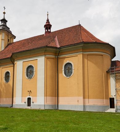 Zdjęcie nr 20: Kościół jest orientowany, murowany z cegły i kamienia, na rzucie podłużnym. Zajmuje powierzchnię około 606 metrów kwadratowych, długość bryły wynosi około 32, a szerokość 14 metrów. Jednonawowy, trójprzęsłowy korpus charakteryzuje środkowe, kwadratowe przęsło z płytkimi apsydami po bokach, wysuwającymi się przed lica elewacji bocznych, na wzór pseudotranseptu (para spłaszczonych apsyd). Przęsło wschodnie, na rzucie prostokąta, z wnękami po bokach, zakończone jest apsydą stanowiącą przestrzeń prezbiterium. Na osi kościoła i przedłużeniu prezbiterium jest piętrowa zakrystia ze skarbcem, natomiast w przedłużeniu przęsła zachodniego wieża ujęta po bokach piętrowymi lokalnościami. Korpus nawowy przekryty jest sklepieniem kolebkowym na gurtach, z lunetami, które w przęśle środkowym, na przecięciu z pseudotranseptem, tworzy rodzaj sklepienia krzyżowego z okrągłym zwierciadłem. Artykulację ścian wewnątrz kościoła stanowią pary pilastrów wspierające przerywane belkowanie. Na zewnątrz ściany korpusu, transeptu i zakrystii artykułują osadzone na niewysokim cokole lizeny wspierające obiegające całość belkowanie. Dodatkowo mury przeprute są owalnymi otworami okiennymi ujętymi profilowanymi obramieniami. Fasadę charakteryzuje w części środkowej ryzalit o skośnych ściankach bocznych oraz podziały podwójnymi i pojedynczymi pilastrami jońskimi, osadzonymi na wysokich cokołach i wspierającymi belkowanie. Do wnętrza kościoła prowadzą trzy otwory drzwiowe – w elewacji południowej, północnej i zachodniej. Drzwi w fasadzie są ujęte dekoracyjnym portalem z parą wąskich pilastrów, zwieńczonych zwężającymi się ku dołowi kapitelami, wspierających gzyms w formie łuku odcinkowego. Całość ujmuje obramienie o fantazyjnym wykroju w górnej partii, którego krawędzie obiega profilowana listwa z parą niewielkich wolut w górnych narożach. Obramienie drzwi wieńczy prosty gzyms odcinkowy nakryty blaszanym daszkiem. Po bokach wejścia znajduje się para kamiennych kropielnic. Powyżej otworu drzwiowego, pole środkowe fasady przeprute zostało oknem w kształcie stojącego prostokąta zamkniętego łukiem odcinkowym, zamurowanego w jednej trzeciej wysokości. Obramienie okna jest w formie pary pilastrów bez baz, wspierających fryz z kluczem pośrodku i parą wsporników wolutowych po bokach, dźwigających odcinkowy gzyms wieńczący. Pod parapetem umieszczono fartuch w kształcie leżącego prostokąta, o wklęsłych dolnych narożach, z dolną krawędzią zdobioną motywem lambrekinu. W skośnych ścianach bocznych ryzalitu znajduje się para zamkniętych półkoliście niszy z figurami św. Piotra po lewej i św. Pawła po prawej stronie. 
Ryzalit wieńczy trójkątny przyczółek z herbem Nowina w tympanonie. Nad belkowaniem, na całej szerokości fasady, znajduje się prosta attyka z odpowiadającymi dolnej strefie elewacji podziałami lizenowymi, wspierającymi wyłamujący się ponad nimi gzyms ozdobiony wazonami. Powyżej wznosi się górne piętro wieży, czworościenne o ściętych narożnikach, nakryte kopulastym hełmem z nasadnikiem.  
Północna, zachodnia i południowa ściana wieży przeprute są otworami okiennymi w kształcie stojącego prostokąta zamkniętego łukiem odcinkowym. Okna mają obramienia w kształcie stojących prostokątów z uszakami w górnych narożach, zwieńczone są belkowaniem w formie łuku odcinkowego z kluczem pośrodku i parą wolutowych wsporników po bokach fryzu. Podwieszenie ma formę fartucha w kształcie leżącego prostokąta o wklęsłych dolnych narożach i dolnej krawędzi zdobionej motywem lambrekinu. Powyżej otworów okiennych znajdują się okrągłe tarcze zegarowe. Pola ściętych naroży wieży zdobi ornamentyka cekinowa i kampanule. Korpus nawowy przykrywa dwuspadowy dach zakończony pięciopołaciowo nad prezbiterium i trójpołaciowo nad końcami transeptu, kryty dachówką. Na skrzyżowaniu korpusu nawowego i transeptu ulokowano obitą blachą wieżyczkę na sygnaturkę. Kolorystyka tynków kościoła utrzymana jest w odcieniu ugru, w dolnej partii różu, detal architektoniczny i ornamentyka w bieli. 

Plac przykościelny otoczony jest murowanym parkanem z usytuowanymi w nim 14 kapliczkami ze stacjami drogi krzyżowej, nakrytymi dwuspadowymi dachami. W jednym z naroży znajduje się niewielka, murowana kaplica grobowa rodziny Romerów o ceglanych ścianach artykułowanych białymi pilastrami i fasadzie ze szczytem ujętym parą spływów i zwieńczonym trójkątnym przyczółkiem.   
