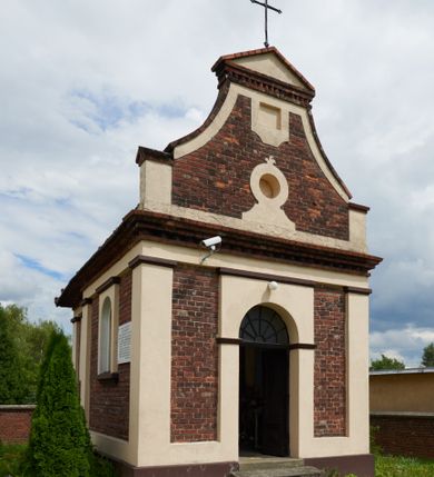 Zdjęcie nr 32: Kościół jest orientowany, murowany z cegły i kamienia, na rzucie podłużnym. Zajmuje powierzchnię około 606 metrów kwadratowych, długość bryły wynosi około 32, a szerokość 14 metrów. Jednonawowy, trójprzęsłowy korpus charakteryzuje środkowe, kwadratowe przęsło z płytkimi apsydami po bokach, wysuwającymi się przed lica elewacji bocznych, na wzór pseudotranseptu (para spłaszczonych apsyd). Przęsło wschodnie, na rzucie prostokąta, z wnękami po bokach, zakończone jest apsydą stanowiącą przestrzeń prezbiterium. Na osi kościoła i przedłużeniu prezbiterium jest piętrowa zakrystia ze skarbcem, natomiast w przedłużeniu przęsła zachodniego wieża ujęta po bokach piętrowymi lokalnościami. Korpus nawowy przekryty jest sklepieniem kolebkowym na gurtach, z lunetami, które w przęśle środkowym, na przecięciu z pseudotranseptem, tworzy rodzaj sklepienia krzyżowego z okrągłym zwierciadłem. Artykulację ścian wewnątrz kościoła stanowią pary pilastrów wspierające przerywane belkowanie. Na zewnątrz ściany korpusu, transeptu i zakrystii artykułują osadzone na niewysokim cokole lizeny wspierające obiegające całość belkowanie. Dodatkowo mury przeprute są owalnymi otworami okiennymi ujętymi profilowanymi obramieniami. Fasadę charakteryzuje w części środkowej ryzalit o skośnych ściankach bocznych oraz podziały podwójnymi i pojedynczymi pilastrami jońskimi, osadzonymi na wysokich cokołach i wspierającymi belkowanie. Do wnętrza kościoła prowadzą trzy otwory drzwiowe – w elewacji południowej, północnej i zachodniej. Drzwi w fasadzie są ujęte dekoracyjnym portalem z parą wąskich pilastrów, zwieńczonych zwężającymi się ku dołowi kapitelami, wspierających gzyms w formie łuku odcinkowego. Całość ujmuje obramienie o fantazyjnym wykroju w górnej partii, którego krawędzie obiega profilowana listwa z parą niewielkich wolut w górnych narożach. Obramienie drzwi wieńczy prosty gzyms odcinkowy nakryty blaszanym daszkiem. Po bokach wejścia znajduje się para kamiennych kropielnic. Powyżej otworu drzwiowego, pole środkowe fasady przeprute zostało oknem w kształcie stojącego prostokąta zamkniętego łukiem odcinkowym, zamurowanego w jednej trzeciej wysokości. Obramienie okna jest w formie pary pilastrów bez baz, wspierających fryz z kluczem pośrodku i parą wsporników wolutowych po bokach, dźwigających odcinkowy gzyms wieńczący. Pod parapetem umieszczono fartuch w kształcie leżącego prostokąta, o wklęsłych dolnych narożach, z dolną krawędzią zdobioną motywem lambrekinu. W skośnych ścianach bocznych ryzalitu znajduje się para zamkniętych półkoliście niszy z figurami św. Piotra po lewej i św. Pawła po prawej stronie. 
Ryzalit wieńczy trójkątny przyczółek z herbem Nowina w tympanonie. Nad belkowaniem, na całej szerokości fasady, znajduje się prosta attyka z odpowiadającymi dolnej strefie elewacji podziałami lizenowymi, wspierającymi wyłamujący się ponad nimi gzyms ozdobiony wazonami. Powyżej wznosi się górne piętro wieży, czworościenne o ściętych narożnikach, nakryte kopulastym hełmem z nasadnikiem.  
Północna, zachodnia i południowa ściana wieży przeprute są otworami okiennymi w kształcie stojącego prostokąta zamkniętego łukiem odcinkowym. Okna mają obramienia w kształcie stojących prostokątów z uszakami w górnych narożach, zwieńczone są belkowaniem w formie łuku odcinkowego z kluczem pośrodku i parą wolutowych wsporników po bokach fryzu. Podwieszenie ma formę fartucha w kształcie leżącego prostokąta o wklęsłych dolnych narożach i dolnej krawędzi zdobionej motywem lambrekinu. Powyżej otworów okiennych znajdują się okrągłe tarcze zegarowe. Pola ściętych naroży wieży zdobi ornamentyka cekinowa i kampanule. Korpus nawowy przykrywa dwuspadowy dach zakończony pięciopołaciowo nad prezbiterium i trójpołaciowo nad końcami transeptu, kryty dachówką. Na skrzyżowaniu korpusu nawowego i transeptu ulokowano obitą blachą wieżyczkę na sygnaturkę. Kolorystyka tynków kościoła utrzymana jest w odcieniu ugru, w dolnej partii różu, detal architektoniczny i ornamentyka w bieli. 

Plac przykościelny otoczony jest murowanym parkanem z usytuowanymi w nim 14 kapliczkami ze stacjami drogi krzyżowej, nakrytymi dwuspadowymi dachami. W jednym z naroży znajduje się niewielka, murowana kaplica grobowa rodziny Romerów o ceglanych ścianach artykułowanych białymi pilastrami i fasadzie ze szczytem ujętym parą spływów i zwieńczonym trójkątnym przyczółkiem.   
