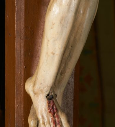 Zdjęcie nr 4: Rzeźba przybita jest trzema gwoździami do prostego krzyża umieszczonego na belce tęczowej. Chrystus ukazany został w typie Cristo morte (umarłego), w lekkim zwisie ciała, o szeroko rozłożonych ramionach przyjmujących kształt delikatnego łuku. Jego głowa opada bezwładnie na prawy bark, nogi ma ugięte w kolanach, skierowane lekko w lewo, w efekcie całe ciało wygina się w pionie w niezbyt wydatny łuk. Stopy skrzyżowane w układzie prawa na lewą. Twarz ma podłużną, o prostym, wąskim nosie, dużych, zamkniętych oczach i niewielkich ustach, okoloną brodą skręconą w dwa pukle oraz pasmami kręconych włosów opadających na ramiona. Na głowie ma koronę cierniową. Jego ciało jest szczupłe, smukłe, o miękko rzeźbionej muskulaturze, silnie podkreślonej w partiach klatki piersiowej, nóg i ramion, z zaznaczonymi śladami męki w postaci broczących rzeźbionymi kroplami krwi ran. Perizonium ma krótkie, ściśle przylegające do ciała, obficie fałdowane zawiązane na prawym biodrze. Polichromia naturalistyczna, perizonium pozłacane. Na pionowej belce krzyża tabliczka z napisem „I.N. / R.I.”. 