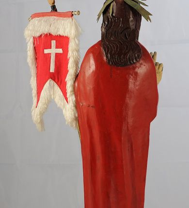 Zdjęcie nr 3: Figura pełnoplastyczna ustawiona na podstawie na planie kwadratu oraz na półkuli. Chrystus stoi frontalnie, w kontrapoście, w lewej ręce trzyma drzewce chorągwi zakończone krzyżem, prawą unosi w geście błogosławieństwa. Jego twarz jest pociągła, o długim, prostym nosie, migdałowatych oczach i niewielkich ustach, okolona krótką brodą i długimi włosami opadającymi na ramiona i plecy. Z tyłu  jego głowy jest dosztukowany nimb promienisty. Chrystus ubrany jest w czerwony płaszcz odsłaniający tors, zapięty na piersi, mocno pofałdowany na wysokości bioder, otaczający postać i przerzucony przez lewe przedramię. Polichromia naturalistyczna, drzewce chorągwi pozłacane.