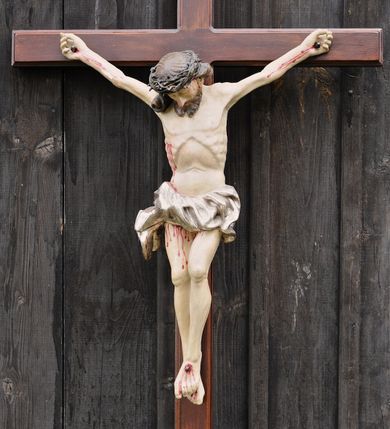 Zdjęcie nr 1: Do krzyża o prostych ramionach przybita trzema gwoździami figura w typie Cristo morte. Ciało Chrystusa jest w lekkim zwisie, o szeroko rozłożonych ramionach, jego głowa opada bezwładnie na prawy bark, lewa noga ugięta jest w kolanie, prawa wyprostowana, stopy skrzyżowane w układzie lewa na prawą. Twarz ma pociągłą, o dużym nosie, zamkniętych oczach i lekko rozchylonych ustach, okoloną krótką, rozdwajającą się brodą oraz długimi włosami opadającymi na prawy bark, skręconymi w jeden, duży pukiel. Na głowie ma koronę cierniową. Jego ciało jest szczupłe, o silnie uwypuklonym kośćcu klatki piersiowej z guzowato rzeźbionymi żebrami i zapadłą płaszczyzną brzucha. Perizonium krótkie, w formie skręconej tkaniny ze zwisem na prawym boku. Na zakończeniu pionowej belki krzyża banderola z napisem „IN/RI”. Polichromia naturalistyczna w partii karnacji, o bladym odcieniu, z zaznaczonymi malowaną krwią ranami, włosy i broda brązowe, perizonium srebrzone. 
