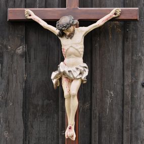 Zdjęcie nr 1: Do krzyża o prostych ramionach przybita trzema gwoździami figura w typie Cristo morte. Ciało Chrystusa jest w lekkim zwisie, o szeroko rozłożonych ramionach, jego głowa opada bezwładnie na prawy bark, lewa noga ugięta jest w kolanie, prawa wyprostowana, stopy skrzyżowane w układzie lewa na prawą. Twarz ma pociągłą, o dużym nosie, zamkniętych oczach i lekko rozchylonych ustach, okoloną krótką, rozdwajającą się brodą oraz długimi włosami opadającymi na prawy bark, skręconymi w jeden, duży pukiel. Na głowie ma koronę cierniową. Jego ciało jest szczupłe, o silnie uwypuklonym kośćcu klatki piersiowej z guzowato rzeźbionymi żebrami i zapadłą płaszczyzną brzucha. Perizonium krótkie, w formie skręconej tkaniny ze zwisem na prawym boku. Na zakończeniu pionowej belki krzyża banderola z napisem „IN/RI”. Polichromia naturalistyczna w partii karnacji, o bladym odcieniu, z zaznaczonymi malowaną krwią ranami, włosy i broda brązowe, perizonium srebrzone. 
