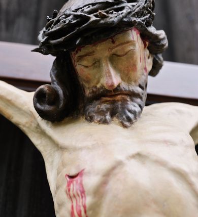 Zdjęcie nr 3: Do krzyża o prostych ramionach przybita trzema gwoździami figura w typie Cristo morte. Ciało Chrystusa jest w lekkim zwisie, o szeroko rozłożonych ramionach, jego głowa opada bezwładnie na prawy bark, lewa noga ugięta jest w kolanie, prawa wyprostowana, stopy skrzyżowane w układzie lewa na prawą. Twarz ma pociągłą, o dużym nosie, zamkniętych oczach i lekko rozchylonych ustach, okoloną krótką, rozdwajającą się brodą oraz długimi włosami opadającymi na prawy bark, skręconymi w jeden, duży pukiel. Na głowie ma koronę cierniową. Jego ciało jest szczupłe, o silnie uwypuklonym kośćcu klatki piersiowej z guzowato rzeźbionymi żebrami i zapadłą płaszczyzną brzucha. Perizonium krótkie, w formie skręconej tkaniny ze zwisem na prawym boku. Na zakończeniu pionowej belki krzyża banderola z napisem „IN/RI”. Polichromia naturalistyczna w partii karnacji, o bladym odcieniu, z zaznaczonymi malowaną krwią ranami, włosy i broda brązowe, perizonium srebrzone. 
