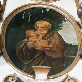 Zdjęcie nr 1: Obraz uzyskał kształt stojącego owalu. W centrum kompozycji w dwóch trzecich ukazano stojącego św. Józefa, piastującego Dzieciątko Jezus. Święty został ujęty w trzech czwartych w prawo. W obu rękach uniesionych na wysokości piersi trzyma małego Jezusa. Józefa ukazano jako starego mężczyznę z bujnymi, siwymi, krótkimi włosami i taką samą brodą. Ma wysuszoną twarz o jasnej karnacji, wydatny nos i usta. Jego spojrzenie półprzymknietych oczu skierowane jest na Dzieciątko. Ubrany jest w ciemnozieloną tunikę oraz mocno udrapowany, ciemnobrązowy płaszcz obficie spowijający jego postać. Głowę świętego okala nimb. Nagie Dzieciątko prawą ręką dotyka brody swojego opiekuna. W lewej natomiast ułożonej wzdłuż tułowia trzyma gałązkę z kwiatami. Mały Jezus ma owalną twarz, drobny nos i wydatne usta. W głębi widać sekwencję z drzewami, górzysty pejzaż oraz niebo zakryte białymi obłokami. 