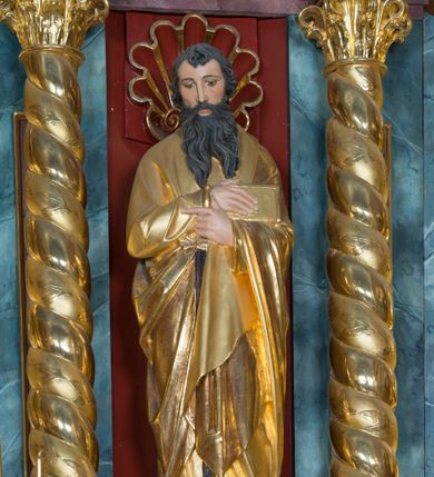 Zdjęcie nr 6: Kamienny ołtarz w jawiszowickim kościele uzyskał kształt prostopadłościanu. Otacza go drewniana obudowa podtrzymująca drewnianą mensę z portatylem. Jego przód zdobi drewniane antepedium ujęte profilowaną ramą z centralnym medalionem z monogramem Marii, otoczonym przez ornament roślinny. Ponad ołtarzem rozpościera się dwukondygnacyjna, architektoniczna nastawa ołtarzowa, flankowana przez dwie bramki. Struktura ołtarza dekorowana jest ciemnozieloną marmoryzacją. Pierwsza kondygnacja retabulum uzyskała trójosiowe założenie wsparte na dwustrefowym cokole, podzielonym płycinami z dekoracją akantową. Artykułują ją dwie pary kolumn o skręconych trzonach i kapitelach kompozytowych. Złocone w całości kolumny podtrzymują belkowanie o wysuniętym gzymsie, wyłamane na ich osi oraz przerwany trójkątny przyczółek. Pole środkowe nastawy wypełnia w całości nisza ujęta profilowaną, złoconą ramą w formie stojącego prostokąta zamkniętego trzema bokami z ośmioboku. W jej wnętrzu znajduje się obraz Matki Boskiej z Dzieciątkiem w typie Matki Boskiej Śnieżnej, zdobiony drewnianą złoconą i srebrzoną sukienką wotywną oraz koronami, a także dwie zasuwy z przedstawieniem św. Marcina, biskupa oraz bł. Salomei. Niszę środkową flankują znajdujące się pomiędzy kolumnami wąskie płyciny zwieńczone konchami. Na ich tle ustawiono figury św. Piotra i św. Pawła. Ponad nimi widoczne są na belkowaniu płaskorzeźbione i złocone girlandy kwiatowe oraz rozety. Na przerwanym przyczółku umieszczono dwie figury siedzących aniołów. Na mensie ołtarza centralnie ustawiono prostopadłościenne tabernakulum w drewnianej obudowie ujęte dwiema kolumienkami kompozytowymi o skręconych trzonach podtrzymujących belkowanie, do którego przymocowano świeczniki na sakramentki. Umieszczony na jego szczycie prosty tron eucharystyczny bez zaplecka flankują dwie figury uskrzydlonych aniołków. Drugą, jednoosiową kondygnację nastawy ujmuje także para złoconych kolumn o skręconych trzonach i kapitelach kompozytowych, ustawionych na cokołach, dźwigających imposty. Pomiędzy kolumnami nad polem z obrazem Wniebowzięcia Matki Boskiej widoczny jest wysunięty fragment gzymsu. Obraz ujęty został złoconą i profilowaną ramą w formie kwadratu o ściętych narożach. Po bokach obrazu na płycinie rozmieszczono złocone dekoracje akantowe. W zwieńczeniu na belkowaniu usytuowano dwa putta flankujące rzeźbę apokaliptycznego baranka leżącego na księdze. Obie kondygnacje ujmują uszaki z akantu suchego. Po bokach nastawy usytuowano dwie bramki flankowane pilastrami. Ich zwężające się ku dołowi trzony podtrzymują nadwieszony łuk półkolisty. Całość zamyka gzyms z centralnie usytuowanym cokołem, na którym stoją figury św. Stanisława i św. Wojciecha. Po ich bokach figur przy ścianach ustawiono rzeźbione i złocone wazony z kwiatami. 