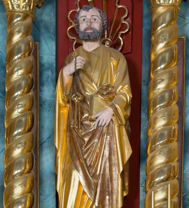 Zdjęcie nr 49: Kamienny ołtarz w jawiszowickim kościele uzyskał kształt prostopadłościanu. Otacza go drewniana obudowa podtrzymująca drewnianą mensę z portatylem. Jego przód zdobi drewniane antepedium ujęte profilowaną ramą z centralnym medalionem z monogramem Marii, otoczonym przez ornament roślinny. Ponad ołtarzem rozpościera się dwukondygnacyjna, architektoniczna nastawa ołtarzowa, flankowana przez dwie bramki. Struktura ołtarza dekorowana jest ciemnozieloną marmoryzacją. Pierwsza kondygnacja retabulum uzyskała trójosiowe założenie wsparte na dwustrefowym cokole, podzielonym płycinami z dekoracją akantową. Artykułują ją dwie pary kolumn o skręconych trzonach i kapitelach kompozytowych. Złocone w całości kolumny podtrzymują belkowanie o wysuniętym gzymsie, wyłamane na ich osi oraz przerwany trójkątny przyczółek. Pole środkowe nastawy wypełnia w całości nisza ujęta profilowaną, złoconą ramą w formie stojącego prostokąta zamkniętego trzema bokami z ośmioboku. W jej wnętrzu znajduje się obraz Matki Boskiej z Dzieciątkiem w typie Matki Boskiej Śnieżnej, zdobiony drewnianą złoconą i srebrzoną sukienką wotywną oraz koronami, a także dwie zasuwy z przedstawieniem św. Marcina, biskupa oraz bł. Salomei. Niszę środkową flankują znajdujące się pomiędzy kolumnami wąskie płyciny zwieńczone konchami. Na ich tle ustawiono figury św. Piotra i św. Pawła. Ponad nimi widoczne są na belkowaniu płaskorzeźbione i złocone girlandy kwiatowe oraz rozety. Na przerwanym przyczółku umieszczono dwie figury siedzących aniołów. Na mensie ołtarza centralnie ustawiono prostopadłościenne tabernakulum w drewnianej obudowie ujęte dwiema kolumienkami kompozytowymi o skręconych trzonach podtrzymujących belkowanie, do którego przymocowano świeczniki na sakramentki. Umieszczony na jego szczycie prosty tron eucharystyczny bez zaplecka flankują dwie figury uskrzydlonych aniołków. Drugą, jednoosiową kondygnację nastawy ujmuje także para złoconych kolumn o skręconych trzonach i kapitelach kompozytowych, ustawionych na cokołach, dźwigających imposty. Pomiędzy kolumnami nad polem z obrazem Wniebowzięcia Matki Boskiej widoczny jest wysunięty fragment gzymsu. Obraz ujęty został złoconą i profilowaną ramą w formie kwadratu o ściętych narożach. Po bokach obrazu na płycinie rozmieszczono złocone dekoracje akantowe. W zwieńczeniu na belkowaniu usytuowano dwa putta flankujące rzeźbę apokaliptycznego baranka leżącego na księdze. Obie kondygnacje ujmują uszaki z akantu suchego. Po bokach nastawy usytuowano dwie bramki flankowane pilastrami. Ich zwężające się ku dołowi trzony podtrzymują nadwieszony łuk półkolisty. Całość zamyka gzyms z centralnie usytuowanym cokołem, na którym stoją figury św. Stanisława i św. Wojciecha. Po ich bokach figur przy ścianach ustawiono rzeźbione i złocone wazony z kwiatami. 