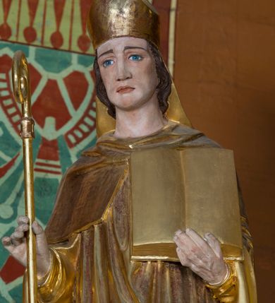 Zdjęcie nr 25: Kamienny ołtarz w jawiszowickim kościele uzyskał kształt prostopadłościanu. Otacza go drewniana obudowa podtrzymująca drewnianą mensę z portatylem. Jego przód zdobi drewniane antepedium ujęte profilowaną ramą z centralnym medalionem z monogramem Marii, otoczonym przez ornament roślinny. Ponad ołtarzem rozpościera się dwukondygnacyjna, architektoniczna nastawa ołtarzowa, flankowana przez dwie bramki. Struktura ołtarza dekorowana jest ciemnozieloną marmoryzacją. Pierwsza kondygnacja retabulum uzyskała trójosiowe założenie wsparte na dwustrefowym cokole, podzielonym płycinami z dekoracją akantową. Artykułują ją dwie pary kolumn o skręconych trzonach i kapitelach kompozytowych. Złocone w całości kolumny podtrzymują belkowanie o wysuniętym gzymsie, wyłamane na ich osi oraz przerwany trójkątny przyczółek. Pole środkowe nastawy wypełnia w całości nisza ujęta profilowaną, złoconą ramą w formie stojącego prostokąta zamkniętego trzema bokami z ośmioboku. W jej wnętrzu znajduje się obraz Matki Boskiej z Dzieciątkiem w typie Matki Boskiej Śnieżnej, zdobiony drewnianą złoconą i srebrzoną sukienką wotywną oraz koronami, a także dwie zasuwy z przedstawieniem św. Marcina, biskupa oraz bł. Salomei. Niszę środkową flankują znajdujące się pomiędzy kolumnami wąskie płyciny zwieńczone konchami. Na ich tle ustawiono figury św. Piotra i św. Pawła. Ponad nimi widoczne są na belkowaniu płaskorzeźbione i złocone girlandy kwiatowe oraz rozety. Na przerwanym przyczółku umieszczono dwie figury siedzących aniołów. Na mensie ołtarza centralnie ustawiono prostopadłościenne tabernakulum w drewnianej obudowie ujęte dwiema kolumienkami kompozytowymi o skręconych trzonach podtrzymujących belkowanie, do którego przymocowano świeczniki na sakramentki. Umieszczony na jego szczycie prosty tron eucharystyczny bez zaplecka flankują dwie figury uskrzydlonych aniołków. Drugą, jednoosiową kondygnację nastawy ujmuje także para złoconych kolumn o skręconych trzonach i kapitelach kompozytowych, ustawionych na cokołach, dźwigających imposty. Pomiędzy kolumnami nad polem z obrazem Wniebowzięcia Matki Boskiej widoczny jest wysunięty fragment gzymsu. Obraz ujęty został złoconą i profilowaną ramą w formie kwadratu o ściętych narożach. Po bokach obrazu na płycinie rozmieszczono złocone dekoracje akantowe. W zwieńczeniu na belkowaniu usytuowano dwa putta flankujące rzeźbę apokaliptycznego baranka leżącego na księdze. Obie kondygnacje ujmują uszaki z akantu suchego. Po bokach nastawy usytuowano dwie bramki flankowane pilastrami. Ich zwężające się ku dołowi trzony podtrzymują nadwieszony łuk półkolisty. Całość zamyka gzyms z centralnie usytuowanym cokołem, na którym stoją figury św. Stanisława i św. Wojciecha. Po ich bokach figur przy ścianach ustawiono rzeźbione i złocone wazony z kwiatami. 