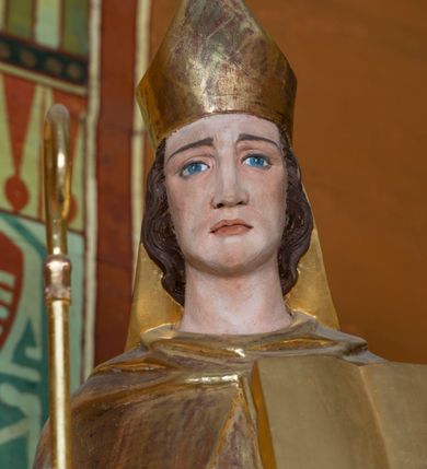 Zdjęcie nr 26: Kamienny ołtarz w jawiszowickim kościele uzyskał kształt prostopadłościanu. Otacza go drewniana obudowa podtrzymująca drewnianą mensę z portatylem. Jego przód zdobi drewniane antepedium ujęte profilowaną ramą z centralnym medalionem z monogramem Marii, otoczonym przez ornament roślinny. Ponad ołtarzem rozpościera się dwukondygnacyjna, architektoniczna nastawa ołtarzowa, flankowana przez dwie bramki. Struktura ołtarza dekorowana jest ciemnozieloną marmoryzacją. Pierwsza kondygnacja retabulum uzyskała trójosiowe założenie wsparte na dwustrefowym cokole, podzielonym płycinami z dekoracją akantową. Artykułują ją dwie pary kolumn o skręconych trzonach i kapitelach kompozytowych. Złocone w całości kolumny podtrzymują belkowanie o wysuniętym gzymsie, wyłamane na ich osi oraz przerwany trójkątny przyczółek. Pole środkowe nastawy wypełnia w całości nisza ujęta profilowaną, złoconą ramą w formie stojącego prostokąta zamkniętego trzema bokami z ośmioboku. W jej wnętrzu znajduje się obraz Matki Boskiej z Dzieciątkiem w typie Matki Boskiej Śnieżnej, zdobiony drewnianą złoconą i srebrzoną sukienką wotywną oraz koronami, a także dwie zasuwy z przedstawieniem św. Marcina, biskupa oraz bł. Salomei. Niszę środkową flankują znajdujące się pomiędzy kolumnami wąskie płyciny zwieńczone konchami. Na ich tle ustawiono figury św. Piotra i św. Pawła. Ponad nimi widoczne są na belkowaniu płaskorzeźbione i złocone girlandy kwiatowe oraz rozety. Na przerwanym przyczółku umieszczono dwie figury siedzących aniołów. Na mensie ołtarza centralnie ustawiono prostopadłościenne tabernakulum w drewnianej obudowie ujęte dwiema kolumienkami kompozytowymi o skręconych trzonach podtrzymujących belkowanie, do którego przymocowano świeczniki na sakramentki. Umieszczony na jego szczycie prosty tron eucharystyczny bez zaplecka flankują dwie figury uskrzydlonych aniołków. Drugą, jednoosiową kondygnację nastawy ujmuje także para złoconych kolumn o skręconych trzonach i kapitelach kompozytowych, ustawionych na cokołach, dźwigających imposty. Pomiędzy kolumnami nad polem z obrazem Wniebowzięcia Matki Boskiej widoczny jest wysunięty fragment gzymsu. Obraz ujęty został złoconą i profilowaną ramą w formie kwadratu o ściętych narożach. Po bokach obrazu na płycinie rozmieszczono złocone dekoracje akantowe. W zwieńczeniu na belkowaniu usytuowano dwa putta flankujące rzeźbę apokaliptycznego baranka leżącego na księdze. Obie kondygnacje ujmują uszaki z akantu suchego. Po bokach nastawy usytuowano dwie bramki flankowane pilastrami. Ich zwężające się ku dołowi trzony podtrzymują nadwieszony łuk półkolisty. Całość zamyka gzyms z centralnie usytuowanym cokołem, na którym stoją figury św. Stanisława i św. Wojciecha. Po ich bokach figur przy ścianach ustawiono rzeźbione i złocone wazony z kwiatami. 