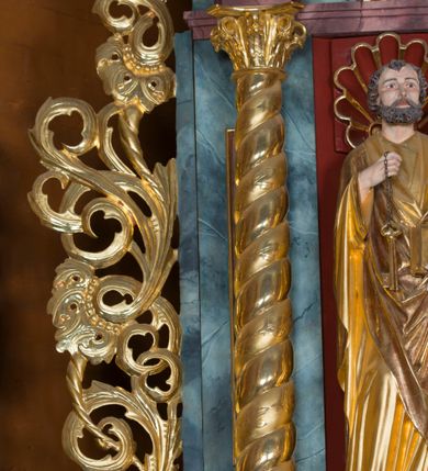 Zdjęcie nr 45: Kamienny ołtarz w jawiszowickim kościele uzyskał kształt prostopadłościanu. Otacza go drewniana obudowa podtrzymująca drewnianą mensę z portatylem. Jego przód zdobi drewniane antepedium ujęte profilowaną ramą z centralnym medalionem z monogramem Marii, otoczonym przez ornament roślinny. Ponad ołtarzem rozpościera się dwukondygnacyjna, architektoniczna nastawa ołtarzowa, flankowana przez dwie bramki. Struktura ołtarza dekorowana jest ciemnozieloną marmoryzacją. Pierwsza kondygnacja retabulum uzyskała trójosiowe założenie wsparte na dwustrefowym cokole, podzielonym płycinami z dekoracją akantową. Artykułują ją dwie pary kolumn o skręconych trzonach i kapitelach kompozytowych. Złocone w całości kolumny podtrzymują belkowanie o wysuniętym gzymsie, wyłamane na ich osi oraz przerwany trójkątny przyczółek. Pole środkowe nastawy wypełnia w całości nisza ujęta profilowaną, złoconą ramą w formie stojącego prostokąta zamkniętego trzema bokami z ośmioboku. W jej wnętrzu znajduje się obraz Matki Boskiej z Dzieciątkiem w typie Matki Boskiej Śnieżnej, zdobiony drewnianą złoconą i srebrzoną sukienką wotywną oraz koronami, a także dwie zasuwy z przedstawieniem św. Marcina, biskupa oraz bł. Salomei. Niszę środkową flankują znajdujące się pomiędzy kolumnami wąskie płyciny zwieńczone konchami. Na ich tle ustawiono figury św. Piotra i św. Pawła. Ponad nimi widoczne są na belkowaniu płaskorzeźbione i złocone girlandy kwiatowe oraz rozety. Na przerwanym przyczółku umieszczono dwie figury siedzących aniołów. Na mensie ołtarza centralnie ustawiono prostopadłościenne tabernakulum w drewnianej obudowie ujęte dwiema kolumienkami kompozytowymi o skręconych trzonach podtrzymujących belkowanie, do którego przymocowano świeczniki na sakramentki. Umieszczony na jego szczycie prosty tron eucharystyczny bez zaplecka flankują dwie figury uskrzydlonych aniołków. Drugą, jednoosiową kondygnację nastawy ujmuje także para złoconych kolumn o skręconych trzonach i kapitelach kompozytowych, ustawionych na cokołach, dźwigających imposty. Pomiędzy kolumnami nad polem z obrazem Wniebowzięcia Matki Boskiej widoczny jest wysunięty fragment gzymsu. Obraz ujęty został złoconą i profilowaną ramą w formie kwadratu o ściętych narożach. Po bokach obrazu na płycinie rozmieszczono złocone dekoracje akantowe. W zwieńczeniu na belkowaniu usytuowano dwa putta flankujące rzeźbę apokaliptycznego baranka leżącego na księdze. Obie kondygnacje ujmują uszaki z akantu suchego. Po bokach nastawy usytuowano dwie bramki flankowane pilastrami. Ich zwężające się ku dołowi trzony podtrzymują nadwieszony łuk półkolisty. Całość zamyka gzyms z centralnie usytuowanym cokołem, na którym stoją figury św. Stanisława i św. Wojciecha. Po ich bokach figur przy ścianach ustawiono rzeźbione i złocone wazony z kwiatami. 