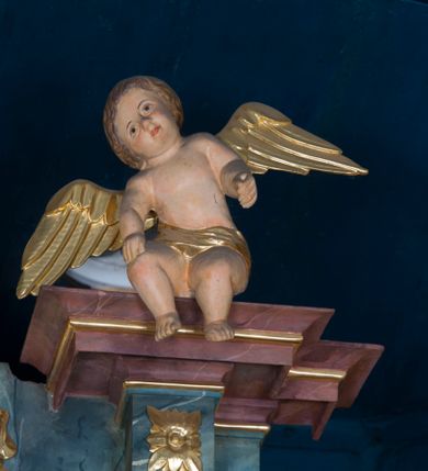 Zdjęcie nr 42: Kamienny ołtarz w jawiszowickim kościele uzyskał kształt prostopadłościanu. Otacza go drewniana obudowa podtrzymująca drewnianą mensę z portatylem. Jego przód zdobi drewniane antepedium ujęte profilowaną ramą z centralnym medalionem z monogramem Marii, otoczonym przez ornament roślinny. Ponad ołtarzem rozpościera się dwukondygnacyjna, architektoniczna nastawa ołtarzowa, flankowana przez dwie bramki. Struktura ołtarza dekorowana jest ciemnozieloną marmoryzacją. Pierwsza kondygnacja retabulum uzyskała trójosiowe założenie wsparte na dwustrefowym cokole, podzielonym płycinami z dekoracją akantową. Artykułują ją dwie pary kolumn o skręconych trzonach i kapitelach kompozytowych. Złocone w całości kolumny podtrzymują belkowanie o wysuniętym gzymsie, wyłamane na ich osi oraz przerwany trójkątny przyczółek. Pole środkowe nastawy wypełnia w całości nisza ujęta profilowaną, złoconą ramą w formie stojącego prostokąta zamkniętego trzema bokami z ośmioboku. W jej wnętrzu znajduje się obraz Matki Boskiej z Dzieciątkiem w typie Matki Boskiej Śnieżnej, zdobiony drewnianą złoconą i srebrzoną sukienką wotywną oraz koronami, a także dwie zasuwy z przedstawieniem św. Marcina, biskupa oraz bł. Salomei. Niszę środkową flankują znajdujące się pomiędzy kolumnami wąskie płyciny zwieńczone konchami. Na ich tle ustawiono figury św. Piotra i św. Pawła. Ponad nimi widoczne są na belkowaniu płaskorzeźbione i złocone girlandy kwiatowe oraz rozety. Na przerwanym przyczółku umieszczono dwie figury siedzących aniołów. Na mensie ołtarza centralnie ustawiono prostopadłościenne tabernakulum w drewnianej obudowie ujęte dwiema kolumienkami kompozytowymi o skręconych trzonach podtrzymujących belkowanie, do którego przymocowano świeczniki na sakramentki. Umieszczony na jego szczycie prosty tron eucharystyczny bez zaplecka flankują dwie figury uskrzydlonych aniołków. Drugą, jednoosiową kondygnację nastawy ujmuje także para złoconych kolumn o skręconych trzonach i kapitelach kompozytowych, ustawionych na cokołach, dźwigających imposty. Pomiędzy kolumnami nad polem z obrazem Wniebowzięcia Matki Boskiej widoczny jest wysunięty fragment gzymsu. Obraz ujęty został złoconą i profilowaną ramą w formie kwadratu o ściętych narożach. Po bokach obrazu na płycinie rozmieszczono złocone dekoracje akantowe. W zwieńczeniu na belkowaniu usytuowano dwa putta flankujące rzeźbę apokaliptycznego baranka leżącego na księdze. Obie kondygnacje ujmują uszaki z akantu suchego. Po bokach nastawy usytuowano dwie bramki flankowane pilastrami. Ich zwężające się ku dołowi trzony podtrzymują nadwieszony łuk półkolisty. Całość zamyka gzyms z centralnie usytuowanym cokołem, na którym stoją figury św. Stanisława i św. Wojciecha. Po ich bokach figur przy ścianach ustawiono rzeźbione i złocone wazony z kwiatami. 