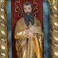 Zdjęcie nr 1: Pełnoplastyczna rzeźba św. Pawła Apostoła została ustawiona na zielonej podstawie na planie kwadratu o ściętych narożach. Święty został ukazany frontalnie w całej postaci. Apostoł ma nieznacznie pochyloną głowę do przodu i ręce skrzyżowane na piersi. Prawą podtrzymuję księgę wspartą o lewe przedramię, trzymając jednocześnie w lewej miecz, skierowany ostrzem ku ziemi. Święty Paweł ma pociągłą twarz okoloną czarnymi włosami i rozdwojoną, długą brodę. Jego spojrzenie skierowane jest w dół. Ma prosty nos, wyraziste oczy i usta. Ubrany jest w przylegającą do ciała tunikę oraz płaszcz narzucony na lewe ramię i podtrzymywany z przodu. Spod tuniki widoczne są bose stopy. W partiach ciała widoczna jest polichromia naturalistyczna. Natomiast szaty i atrybuty są złocone. 