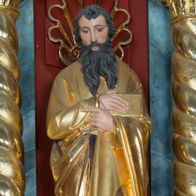 Zdjęcie nr 1: Pełnoplastyczna rzeźba św. Pawła Apostoła została ustawiona na zielonej podstawie na planie kwadratu o ściętych narożach. Święty został ukazany frontalnie w całej postaci. Apostoł ma nieznacznie pochyloną głowę do przodu i ręce skrzyżowane na piersi. Prawą podtrzymuję księgę wspartą o lewe przedramię, trzymając jednocześnie w lewej miecz, skierowany ostrzem ku ziemi. Święty Paweł ma pociągłą twarz okoloną czarnymi włosami i rozdwojoną, długą brodę. Jego spojrzenie skierowane jest w dół. Ma prosty nos, wyraziste oczy i usta. Ubrany jest w przylegającą do ciała tunikę oraz płaszcz narzucony na lewe ramię i podtrzymywany z przodu. Spod tuniki widoczne są bose stopy. W partiach ciała widoczna jest polichromia naturalistyczna. Natomiast szaty i atrybuty są złocone. 