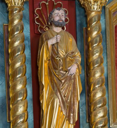Zdjęcie nr 3: Pełnoplastyczna rzeźba ustawiona na zielonej podstawie na planie kwadratu o ściętych narożach przedstawia św. Piotra Apostoła. Święty został ukazany frontalnie w nieznacznym kontrapoście z prawą ręką uniesioną na wysokość piersi, w której trzyma zawieszone na łańcuszku dwa złote klucze. Lewą ręką podtrzymuje połę płaszcza oraz księgę przyciśnięte do ciała powyżej bioder. Apostoł ma owalną twarz o wyrazistych rysach, otoczoną kędzierzawym, krótkim szpakowatym zarostem i włosami. Jego spojrzenie skierowane jest przed siebie. Ma prosty nos i wydatne usta. Ubrany jest w przylegającą do ciała tunikę oraz płaszcz narzucony na prawe ramię i podtrzymywany z przodu. Spod tuniki widoczne są obute w sandały bose stopy. Obie szaty są silnie drapowane. W partiach ciała widoczna jest naturalistyczna polichromia. Natomiast ubranie i atrybuty zostały wyzłocone.