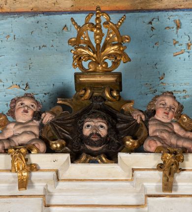 Zdjęcie nr 7: Epitafium uzyskało formę jednokondygnacyjnej, trójosiowej struktury architektonicznej z podstawą i zwieńczeniem, flankowanej po bokach fantazyjnymi uszakami. Część środkową tworzą trzy aedicule rozdzielone dwiema złoconymi kolumnami o korynckich kapitelach i trzonach dekorowanych festonami, a w dolnych partiach pierścieniami. Kolumny podtrzymują pełne belkowanie przechodzące przez całą szerokości kondygnacji, wyłamane nad osiami bocznymi. Same zaś stoją na cokole, który stanowi równocześnie wyłamany gzyms dla podstawy. Pole osi środkowej otrzymało kształt aediculi w formie stojącego prostokąta ze schodkowym zamknięciem u góry, wypełnionym ażurowym, złoconym maswerkiem. Jej wnętrze wypełnia płaskorzeźbione słońce pośród chmur na malowanym tle nieba. Poniżej ukazano panoramę Jerozolimy. Przed aediculą ustawiono na postumencie drewniany krzyż. Na osiach bocznych znalazły się nisze zwieńczone złotymi muszlami oraz złoconą, rytą ornamentyką z motywem czteroliścia. Pierwotnie znajdowały się tu rzeźby Mojżesza i Jana Chrzciciela. Całość po bokach flankują fantazyjne uszaki utworzone ornamentu rollwerkowego oraz z widocznych z profilu półpostaci maurów podtrzymujących belkowanie. Pole uszaków wypełniają pionowo ułożone owalne kartusze o czerwonych polach, stanowiące tło dla dwóch par tarczy herbowych z klejnotami. Z lewej umieszczono herb Dołęga, a z prawej herb Jastrzębiec (bez klejnotu). Po zewnętrznych stronach na belkowaniu ustawiono dwa półsiedzące uskrzydlone anioły (zachował się tylko anioł z prawej strony). Jednocześnie postacie aniołów flankują zwieńczenie epitafium, które tworzy aedicula wypełniona złotą muszlą oraz rytym złoconym ornamentem z motywem czteroliścia. Flankują ją dwa pilastry podtrzymujące wyłamane belkowanie na ich osi. W aediculi ustawiono pełnoplastyczną rzeźbę stojącej kobiety. Została ona ukazana w wydatnym kontrapoście z tułowiem skręconym w lewo, z głową ujętą w trzech czwartych w prawo. Kobieta w podniesionej prawej ręce trzyma srebrny kielich, natomiast w opuszczonej i wspartej o wysuniętą tanecznie lewą nogę otwartą księgę. Postać ma owalną twarz o jasnej karnacji i rumianych policzkach z prostym nosem i wydatnymi ustami. Jej głowę otaczają falujące, brązowe włosy opadające na plecy i  odsłaniające uszy. Ubrana jest w złoconą, mocno drapowaną suknię, która odsłania wysuniętą nogę. Po bokach pilastrów widoczne są dwa uszaki. Na szczycie zwieńczenia dwa pulchne putta prezentują chustę Weroniki, która została równocześnie przytwierdzona do wysokiego impostu wspierającego ażurowy, złocony kwiaton. Na chuście wyobrażono płaskorzeźbioną głowę Chrystusa w cierniowej koronie. Zbawiciel ma owalną twarz z szeroko otwartymi oczami, wydatnym nosem i półotwartymi ustami. Otaczają ją kręcone brązowe włosy oraz podobna, krótka broda. Podstawę epitafium tworzy wykrojona po bokach struktura, w której centrum umieszczono fantazyjnie wyciętą drewnianą, czarną tablicę ze złotym łacińskim napisem "O HOMO FVI QVOD ES SVM QVOD ERIS / NVNC DE(M)VM VIVERE CO(E)PI, MORI DESII, VITA MIHI / PRIOR MORTE(M), MORS PRIA(M) VITA(M) SECV(N)DA(M), QVAE NU(N) QVA(M) / EST I(N)TERI TVRA DEDIT, MO(R)TALITATES  MEOR, HO(C) MIHI / EST ET VXORI MO(S) VENTV(S) POSVI, VIPOST QV(E)ALETHIVERA DVCEDI / NELVSOS, ET CARNIS EXVVIIS SO(L)VTOS  ABHOC PELAG  SECVRA / GLAVSTRA SVB IRE IVABIT, HIC MORTALE DIMIDIVM N(OST)RI, IMMORTA/LE(M) EXPECT ET IM(M)ORTALITATEM, E QVOS VITA CONIVCTOS TENVIT / MORS IDIVISOS CVSTODIRET, SI PIVS ES, PIAS PRECES ADDE, ET / HIC HV(M)O SVB HVMO QVIETA[M], ANIMAE IN COELESTI PATRIA / LETAM  QVIETEM APPRECARE "NICOLAVS CORNITIVS DE / MAGNA POREMBA ET BEATA DE MIROW CONSOR/TES SE(M)PER VAIESL[?]" / A(NNO) D(OMINI) 1611 P(ATRONVS) P(OSVIT)". Tablicę umieszczono w kartuszu rollwerkowym pomiędzy dwiema konsolami zdobionymi pierwotnie uskrzydlonymi główkami aniołków, podtrzymującymi belkowanie z krzyżem. Poniżej tablicy zastosowano odwrócony łuk odcinkowy z podwieszonym kartuszem rollwerkowym zawieszonym na festonach. W jego wnętrzu przedstawiono tabliczkę z napisem „VITA FUGIT VT HORA”, a po niżej trupią czaszkę ze skrzyżowanymi piszczelami.  
