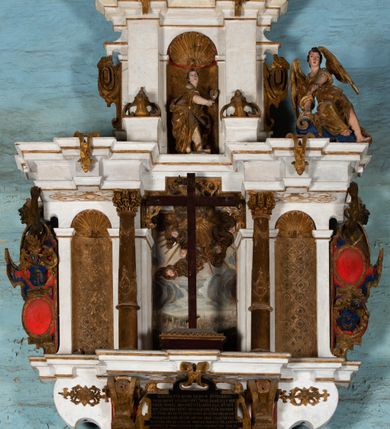 Zdjęcie nr 2: Epitafium uzyskało formę jednokondygnacyjnej, trójosiowej struktury architektonicznej z podstawą i zwieńczeniem, flankowanej po bokach fantazyjnymi uszakami. Część środkową tworzą trzy aedicule rozdzielone dwiema złoconymi kolumnami o korynckich kapitelach i trzonach dekorowanych festonami, a w dolnych partiach pierścieniami. Kolumny podtrzymują pełne belkowanie przechodzące przez całą szerokości kondygnacji, wyłamane nad osiami bocznymi. Same zaś stoją na cokole, który stanowi równocześnie wyłamany gzyms dla podstawy. Pole osi środkowej otrzymało kształt aediculi w formie stojącego prostokąta ze schodkowym zamknięciem u góry, wypełnionym ażurowym, złoconym maswerkiem. Jej wnętrze wypełnia płaskorzeźbione słońce pośród chmur na malowanym tle nieba. Poniżej ukazano panoramę Jerozolimy. Przed aediculą ustawiono na postumencie drewniany krzyż. Na osiach bocznych znalazły się nisze zwieńczone złotymi muszlami oraz złoconą, rytą ornamentyką z motywem czteroliścia. Pierwotnie znajdowały się tu rzeźby Mojżesza i Jana Chrzciciela. Całość po bokach flankują fantazyjne uszaki utworzone ornamentu rollwerkowego oraz z widocznych z profilu półpostaci maurów podtrzymujących belkowanie. Pole uszaków wypełniają pionowo ułożone owalne kartusze o czerwonych polach, stanowiące tło dla dwóch par tarczy herbowych z klejnotami. Z lewej umieszczono herb Dołęga, a z prawej herb Jastrzębiec (bez klejnotu). Po zewnętrznych stronach na belkowaniu ustawiono dwa półsiedzące uskrzydlone anioły (zachował się tylko anioł z prawej strony). Jednocześnie postacie aniołów flankują zwieńczenie epitafium, które tworzy aedicula wypełniona złotą muszlą oraz rytym złoconym ornamentem z motywem czteroliścia. Flankują ją dwa pilastry podtrzymujące wyłamane belkowanie na ich osi. W aediculi ustawiono pełnoplastyczną rzeźbę stojącej kobiety. Została ona ukazana w wydatnym kontrapoście z tułowiem skręconym w lewo, z głową ujętą w trzech czwartych w prawo. Kobieta w podniesionej prawej ręce trzyma srebrny kielich, natomiast w opuszczonej i wspartej o wysuniętą tanecznie lewą nogę otwartą księgę. Postać ma owalną twarz o jasnej karnacji i rumianych policzkach z prostym nosem i wydatnymi ustami. Jej głowę otaczają falujące, brązowe włosy opadające na plecy i  odsłaniające uszy. Ubrana jest w złoconą, mocno drapowaną suknię, która odsłania wysuniętą nogę. Po bokach pilastrów widoczne są dwa uszaki. Na szczycie zwieńczenia dwa pulchne putta prezentują chustę Weroniki, która została równocześnie przytwierdzona do wysokiego impostu wspierającego ażurowy, złocony kwiaton. Na chuście wyobrażono płaskorzeźbioną głowę Chrystusa w cierniowej koronie. Zbawiciel ma owalną twarz z szeroko otwartymi oczami, wydatnym nosem i półotwartymi ustami. Otaczają ją kręcone brązowe włosy oraz podobna, krótka broda. Podstawę epitafium tworzy wykrojona po bokach struktura, w której centrum umieszczono fantazyjnie wyciętą drewnianą, czarną tablicę ze złotym łacińskim napisem "O HOMO FVI QVOD ES SVM QVOD ERIS / NVNC DE(M)VM VIVERE CO(E)PI, MORI DESII, VITA MIHI / PRIOR MORTE(M), MORS PRIA(M) VITA(M) SECV(N)DA(M), QVAE NU(N) QVA(M) / EST I(N)TERI TVRA DEDIT, MO(R)TALITATES  MEOR, HO(C) MIHI / EST ET VXORI MO(S) VENTV(S) POSVI, VIPOST QV(E)ALETHIVERA DVCEDI / NELVSOS, ET CARNIS EXVVIIS SO(L)VTOS  ABHOC PELAG  SECVRA / GLAVSTRA SVB IRE IVABIT, HIC MORTALE DIMIDIVM N(OST)RI, IMMORTA/LE(M) EXPECT ET IM(M)ORTALITATEM, E QVOS VITA CONIVCTOS TENVIT / MORS IDIVISOS CVSTODIRET, SI PIVS ES, PIAS PRECES ADDE, ET / HIC HV(M)O SVB HVMO QVIETA[M], ANIMAE IN COELESTI PATRIA / LETAM  QVIETEM APPRECARE "NICOLAVS CORNITIVS DE / MAGNA POREMBA ET BEATA DE MIROW CONSOR/TES SE(M)PER VAIESL[?]" / A(NNO) D(OMINI) 1611 P(ATRONVS) P(OSVIT)". Tablicę umieszczono w kartuszu rollwerkowym pomiędzy dwiema konsolami zdobionymi pierwotnie uskrzydlonymi główkami aniołków, podtrzymującymi belkowanie z krzyżem. Poniżej tablicy zastosowano odwrócony łuk odcinkowy z podwieszonym kartuszem rollwerkowym zawieszonym na festonach. W jego wnętrzu przedstawiono tabliczkę z napisem „VITA FUGIT VT HORA”, a po niżej trupią czaszkę ze skrzyżowanymi piszczelami.  
