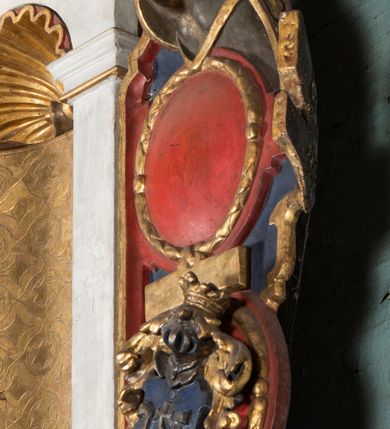 Zdjęcie nr 14: Epitafium uzyskało formę jednokondygnacyjnej, trójosiowej struktury architektonicznej z podstawą i zwieńczeniem, flankowanej po bokach fantazyjnymi uszakami. Część środkową tworzą trzy aedicule rozdzielone dwiema złoconymi kolumnami o korynckich kapitelach i trzonach dekorowanych festonami, a w dolnych partiach pierścieniami. Kolumny podtrzymują pełne belkowanie przechodzące przez całą szerokości kondygnacji, wyłamane nad osiami bocznymi. Same zaś stoją na cokole, który stanowi równocześnie wyłamany gzyms dla podstawy. Pole osi środkowej otrzymało kształt aediculi w formie stojącego prostokąta ze schodkowym zamknięciem u góry, wypełnionym ażurowym, złoconym maswerkiem. Jej wnętrze wypełnia płaskorzeźbione słońce pośród chmur na malowanym tle nieba. Poniżej ukazano panoramę Jerozolimy. Przed aediculą ustawiono na postumencie drewniany krzyż. Na osiach bocznych znalazły się nisze zwieńczone złotymi muszlami oraz złoconą, rytą ornamentyką z motywem czteroliścia. Pierwotnie znajdowały się tu rzeźby Mojżesza i Jana Chrzciciela. Całość po bokach flankują fantazyjne uszaki utworzone ornamentu rollwerkowego oraz z widocznych z profilu półpostaci maurów podtrzymujących belkowanie. Pole uszaków wypełniają pionowo ułożone owalne kartusze o czerwonych polach, stanowiące tło dla dwóch par tarczy herbowych z klejnotami. Z lewej umieszczono herb Dołęga, a z prawej herb Jastrzębiec (bez klejnotu). Po zewnętrznych stronach na belkowaniu ustawiono dwa półsiedzące uskrzydlone anioły (zachował się tylko anioł z prawej strony). Jednocześnie postacie aniołów flankują zwieńczenie epitafium, które tworzy aedicula wypełniona złotą muszlą oraz rytym złoconym ornamentem z motywem czteroliścia. Flankują ją dwa pilastry podtrzymujące wyłamane belkowanie na ich osi. W aediculi ustawiono pełnoplastyczną rzeźbę stojącej kobiety. Została ona ukazana w wydatnym kontrapoście z tułowiem skręconym w lewo, z głową ujętą w trzech czwartych w prawo. Kobieta w podniesionej prawej ręce trzyma srebrny kielich, natomiast w opuszczonej i wspartej o wysuniętą tanecznie lewą nogę otwartą księgę. Postać ma owalną twarz o jasnej karnacji i rumianych policzkach z prostym nosem i wydatnymi ustami. Jej głowę otaczają falujące, brązowe włosy opadające na plecy i  odsłaniające uszy. Ubrana jest w złoconą, mocno drapowaną suknię, która odsłania wysuniętą nogę. Po bokach pilastrów widoczne są dwa uszaki. Na szczycie zwieńczenia dwa pulchne putta prezentują chustę Weroniki, która została równocześnie przytwierdzona do wysokiego impostu wspierającego ażurowy, złocony kwiaton. Na chuście wyobrażono płaskorzeźbioną głowę Chrystusa w cierniowej koronie. Zbawiciel ma owalną twarz z szeroko otwartymi oczami, wydatnym nosem i półotwartymi ustami. Otaczają ją kręcone brązowe włosy oraz podobna, krótka broda. Podstawę epitafium tworzy wykrojona po bokach struktura, w której centrum umieszczono fantazyjnie wyciętą drewnianą, czarną tablicę ze złotym łacińskim napisem &quot;O HOMO FVI QVOD ES SVM QVOD ERIS / NVNC DE(M)VM VIVERE CO(E)PI, MORI DESII, VITA MIHI / PRIOR MORTE(M), MORS PRIA(M) VITA(M) SECV(N)DA(M), QVAE NU(N) QVA(M) / EST I(N)TERI TVRA DEDIT, MO(R)TALITATES  MEOR, HO(C) MIHI / EST ET VXORI MO(S) VENTV(S) POSVI, VIPOST QV(E)ALETHIVERA DVCEDI / NELVSOS, ET CARNIS EXVVIIS SO(L)VTOS  ABHOC PELAG  SECVRA / GLAVSTRA SVB IRE IVABIT, HIC MORTALE DIMIDIVM N(OST)RI, IMMORTA/LE(M) EXPECT ET IM(M)ORTALITATEM, E QVOS VITA CONIVCTOS TENVIT / MORS IDIVISOS CVSTODIRET, SI PIVS ES, PIAS PRECES ADDE, ET / HIC HV(M)O SVB HVMO QVIETA[M], ANIMAE IN COELESTI PATRIA / LETAM  QVIETEM APPRECARE &quot;NICOLAVS CORNITIVS DE / MAGNA POREMBA ET BEATA DE MIROW CONSOR/TES SE(M)PER VAIESL[?]&quot; / A(NNO) D(OMINI) 1611 P(ATRONVS) P(OSVIT)&quot;. Tablicę umieszczono w kartuszu rollwerkowym pomiędzy dwiema konsolami zdobionymi pierwotnie uskrzydlonymi główkami aniołków, podtrzymującymi belkowanie z krzyżem. Poniżej tablicy zastosowano odwrócony łuk odcinkowy z podwieszonym kartuszem rollwerkowym zawieszonym na festonach. W jego wnętrzu przedstawiono tabliczkę z napisem „VITA FUGIT VT HORA”, a po niżej trupią czaszkę ze skrzyżowanymi piszczelami.  
