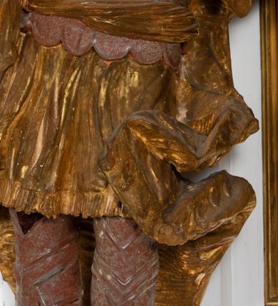 Zdjęcie nr 1: Ustawiona na cokole o nieregularnym planie, pełnoplastyczna rzeźba drążona, ukazuje anonimowego świętego króla. Figura zwrócona jest do widza frontalnie, z głową i torsem wychylonym w lewo i skierowanymi w układzie trzech czwartych. Król stoi w kontrapoście z rękami rozłożonymi na boki. Jest to dojrzały mężczyzna o szczupłej twarzy i podkreślonych kościach policzkowych i linii łuków brwiowych. Charakteryzuje się silnie zadartym, wąskim nosem, pełnymi i lekko rozchylonymi wargami. Jego niewielkie, okrągłe oczy skierowane są w górę. Twarz okala silnie skręcona w dwa pukle broda oraz krótkie, kręcone włosy. Monarcha ubrany jest w tunikę lamowaną frędzlą i sięgającą kolan. Na niej nałożony ma pancerz lekkiej zbroi płytowej z zarękawiami przewiązany w pasie szarfą, za którą ma wetknięte dwie gałązki palmowe. Jego nogi ochraniają nadgolennice i trzewiki. Na ramionach ma narzucony płaszcz podbity gronostajem, zapięty na piersi, którego poły rozwiewają się po bokach postaci. Jego głowę zdobi zamknięta korona o stylizowanych sterczynach. Partie odsłoniętego ciała pokrywa naturalistyczna polichromia, natomiast korona i płaszcz są złocone, a elementy zbroi srebrzone.