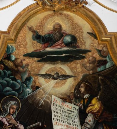 Zdjęcie nr 2: Obraz uzyskał formę stojącego prostokąta zamkniętego u góry łukiem odcinkowym nadwieszonym z uskokami, ujętego profilowaną ramą. W środkowej części kompozycji przedstawiono scenę zwiastowania Najświętszej Marii Pannie.
Marię ujętą w trzech czwartych w prawo wyobrażono klęczącą na klęczniku z lewej strony kompozycji. Lewą rękę przycisk do piersi, a prawą nieznacznie odsuwa od siebie. Jest to młoda dziewczyna po owalnej twarzy z jasną karnacją, wydatnym nosem i ustami z mocno drapowaną białą chusta na głowie zakrywającą jest włosy. Głowę Marii okala nimb. Madonna ubrań jest w bladofioletową suknię oraz ciemnozielony płaszcz nieznacznie zsuwający się z jej prawego ramienia, którego poła okrywa jej kolana. Na drewnianym klęczniku leży otwarta księga. Klęczący przed nią uskrzydlony Archanioł Gabriel ujęty w trzech czwartych w lewo klęczy na szarobiałych obłokach. Obiema rękami prezentuje Marii pergaminowy list zakończony u dołu zawieszoną na przytwierdzonych do jego rogów sznurku okrągłą, woskową pieczęcią zdobioną symbolem Trójcy Świętej. Na liście umieszczono kaligraficzne wypisane pozdrowienie anielskie: „AVE MARIA GRA/TIA PLENA DOMINVS / TECVM BENEDICTA TV / IN MVLIERIBVS ET / BENEDICTVS TRV/CTVS [FRVCTVS] VENTRIS TVI / JESVS CHRISTVS”. Jego młodzieńcza twarz o jasnej karnacji z wydatnym nosem i ustami widoczna jest z profilu. Otaczają ją falujące brązowe włosy, spływające na jego plecy spod złotego diademu dekorowanego na przędzie klejnotem z krzyżykiem. Gabriel ubrany jest w jasną tunikę dekorowaną drobnymi kwiatuszkami oraz złocistą szatę z podwiniętymi rękawami opadającą na jego plecy i przewiązaną skrzyżowaną na piersi ciemnozieloną stułą o końcach zdobionych złotymi chwostami. Pomiędzy obłokami na których klęczy archanioł widoczne są uskrzydlone główki anielskie. W górnej części kompozycji widać otwarte niebiosa okolone po zewnętrznej niebieskoszarymi obłokami z igrającymi w nich aniołkami adorującymi widocznego w połowie na obłoku Boga Ojca. Stworzyciel został ukazany na jasnym tle utworzonym z niezliczonej liczby ułożonych koncentrycznie uskrzydlonych główek anielskich. Bóg Ojciec został ujęty frontalnie z uniesioną prawą ręką oraz niebieskim globem podtrzymywanym lewą na szaroniebieskim obłoku. Jest to starzec z obfitą siwą brodą i włosami oraz zamkniętymi oczami. Ubrany jest w ciemnoniebieską tunikę oraz przerzucony prze lewe ramię bladoszkarłatny płaszcz. Poniże ponad głowami Marii i Archanioła w świetlanym otoku przedstawiono gołębicę Ducha Świętego, od której snop świtała pada na Marię. W dolnej części kompozycji wyobrażono siedzących sześciu proroków i królów starotestamentalnych trzymających prostokątne tablice z napisami. Widoczny w centrum król Dawid gra na złocistej harfie. Są to starsi mężczyźni w orientalnych strojach. Dwóch z nich ma złote korony, dwóch wzorzyste turbany, a dwaj pozostali mają głowy okryte tkaninami. Ich twarze okalają siwe brody, bądź też krótkie brody brązowe. W prawym dolnym rogu widoczna jest sygnatura „B. Weiss 1896.”