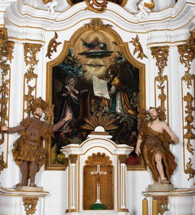 Zdjęcie nr 1: Kamienny ołtarz zamknięto w drewnianej obudowie, nakrywając go  drewnianą mensą z portatylem. Stipes ołtarzowy uzyskał kształt prostopadłościanu. Jego przód zdobi drewniane antepedium ujęte profilowaną ramą z malowanym chrystogramem "IHS" w glorii w polu. Na mensie ołtarza usytuowano tabernakulum w formie stojącego prostopadłościanu o wypukłym froncie i wklęsłych bokach wspierającego się na cokole. Jego przód ujmuje para kolumn podtrzymujących niepełne belkowanie, wyłamane nad ścianą frontową na kształt łuku odcinkowego nadwieszonego. Na froncie zamontowano obrotową, dwustronną niszę ujętą ramą w formie stojącego prostokąta zamkniętego łukiem półkolistym, wielolistnym. Nisze bębna zwieńczone zostały złoconymi konchami. Na tabernakulum usytuowano tron eucharystyczny w formie cokołu z leżącą księgą o siedmiu pieczęciach w glorii. Retabulum ołtarzowe wzniesiono na planie półowalu i polichromowano je na biało. Jest to architektoniczna, jednokondygnacyjna, jednoosiowa struktura ze zwieńczeniem. Po bokach flankują ją bramki ustawione na dwustrefowym, tralkowym, wklęsło-wypukłym cokole. Kondygnacja została ujęta dwiema parami pilastrów zwróconych delikatnie do wewnątrz oraz silnie wysuniętą do przodu parą kolumn o kapitelach kompozytowych. Podpory dźwigają pełne belkowanie o wklęsło-wypukłej linii. Nad polem środkowym belkowanie jest połączone gzymsem przyjmującym formę łuku falistego i wyłamane na osiach podpór. Kondygnacje ujmują spływy wolutowe połączone z łukowato wygiętymi wolutami podtrzymywanymi przez wysokie tralkowe cokoły, tworząc bramki ołtarza. W polu środkowym umieszczono obraz Zwiastowania ujęty profilowaną, złoconą ramą w formie stojącego prostokąta zamkniętego łukiem półkolistym nadwieszonym z uskokiem. Zwieńczenie uzyskało formę leżącego prostokąta flankowanego parą pilastrów zwróconych do wewnątrz oraz parą pilastrów zwróconych na zewnątrz, których trzony przechodzą w spływy wolutowe opadające na belkowanie. Pilastry dźwigają niepełne, wklęsło-wypukłe belkowanie przyjmujące nad polem formę łuku falistego. Całość wieńczy kartusz rokokowy z chrystogramem "IHS". W polu zwieńczenia znalazł się obraz św. Andrzeja w profilowanej, złoconej ramie o fantazyjnej formie zbliżonej do stojącego prostokąta. Pilastry kondygnacji ozdobiono kapitelami z rocaille'ów, a ich trzony udekorowano złoconymi, rokokowymi panneau ze zwisami utworzonymi z rocaille'ów, rozet i liści. Na ich tle usytuowano figury świętego króla i św. Jana Chrzciciela. Rzeźby stoją na górnej strefie cokołu na wspornikach z rocaille. Na ramie obrazu w polu środkowym, w przyłuczach i na belkowaniu znalazły się ornamenty roślinne. Z kolei na wolutowych łukach bramek umieszczono rokokowe wazony oraz pary figur aniołów z kartuszami. Na belkowaniu i wolutach zwieńczenia znajdują się dwie pary puttów. Także trzony pilastrów zwieńczenia dekorowane są złoconymi zwisami z rocaille'ów i kwiatów. Pole wokół obrazu św. Andrzeja zostało ozdobione fragmentami rocaille'ów. Pod gzymsem koronującym powyżej obrazu, podwieszono lambrekin, zdobiony przy górnej krawędzi złoconymi liśćmi i rocaille'm. 