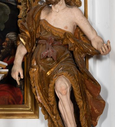 Zdjęcie nr 13: Kamienny ołtarz zamknięto w drewnianej obudowie, nakrywając go  drewnianą mensą z portatylem. Stipes ołtarzowy uzyskał kształt prostopadłościanu. Jego przód zdobi drewniane antepedium ujęte profilowaną ramą z malowanym chrystogramem &quot;IHS&quot; w glorii w polu. Na mensie ołtarza usytuowano tabernakulum w formie stojącego prostopadłościanu o wypukłym froncie i wklęsłych bokach wspierającego się na cokole. Jego przód ujmuje para kolumn podtrzymujących niepełne belkowanie, wyłamane nad ścianą frontową na kształt łuku odcinkowego nadwieszonego. Na froncie zamontowano obrotową, dwustronną niszę ujętą ramą w formie stojącego prostokąta zamkniętego łukiem półkolistym, wielolistnym. Nisze bębna zwieńczone zostały złoconymi konchami. Na tabernakulum usytuowano tron eucharystyczny w formie cokołu z leżącą księgą o siedmiu pieczęciach w glorii. Retabulum ołtarzowe wzniesiono na planie półowalu i polichromowano je na biało. Jest to architektoniczna, jednokondygnacyjna, jednoosiowa struktura ze zwieńczeniem. Po bokach flankują ją bramki ustawione na dwustrefowym, tralkowym, wklęsło-wypukłym cokole. Kondygnacja została ujęta dwiema parami pilastrów zwróconych delikatnie do wewnątrz oraz silnie wysuniętą do przodu parą kolumn o kapitelach kompozytowych. Podpory dźwigają pełne belkowanie o wklęsło-wypukłej linii. Nad polem środkowym belkowanie jest połączone gzymsem przyjmującym formę łuku falistego i wyłamane na osiach podpór. Kondygnacje ujmują spływy wolutowe połączone z łukowato wygiętymi wolutami podtrzymywanymi przez wysokie tralkowe cokoły, tworząc bramki ołtarza. W polu środkowym umieszczono obraz Zwiastowania ujęty profilowaną, złoconą ramą w formie stojącego prostokąta zamkniętego łukiem półkolistym nadwieszonym z uskokiem. Zwieńczenie uzyskało formę leżącego prostokąta flankowanego parą pilastrów zwróconych do wewnątrz oraz parą pilastrów zwróconych na zewnątrz, których trzony przechodzą w spływy wolutowe opadające na belkowanie. Pilastry dźwigają niepełne, wklęsło-wypukłe belkowanie przyjmujące nad polem formę łuku falistego. Całość wieńczy kartusz rokokowy z chrystogramem &quot;IHS&quot;. W polu zwieńczenia znalazł się obraz św. Andrzeja w profilowanej, złoconej ramie o fantazyjnej formie zbliżonej do stojącego prostokąta. Pilastry kondygnacji ozdobiono kapitelami z rocaille&#039;ów, a ich trzony udekorowano złoconymi, rokokowymi panneau ze zwisami utworzonymi z rocaille&#039;ów, rozet i liści. Na ich tle usytuowano figury świętego króla i św. Jana Chrzciciela. Rzeźby stoją na górnej strefie cokołu na wspornikach z rocaille. Na ramie obrazu w polu środkowym, w przyłuczach i na belkowaniu znalazły się ornamenty roślinne. Z kolei na wolutowych łukach bramek umieszczono rokokowe wazony oraz pary figur aniołów z kartuszami. Na belkowaniu i wolutach zwieńczenia znajdują się dwie pary puttów. Także trzony pilastrów zwieńczenia dekorowane są złoconymi zwisami z rocaille&#039;ów i kwiatów. Pole wokół obrazu św. Andrzeja zostało ozdobione fragmentami rocaille&#039;ów. Pod gzymsem koronującym powyżej obrazu, podwieszono lambrekin, zdobiony przy górnej krawędzi złoconymi liśćmi i rocaille&#039;m. 