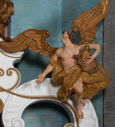 Zdjęcie nr 20: Kamienny ołtarz zamknięto w drewnianej obudowie, nakrywając go  drewnianą mensą z portatylem. Stipes ołtarzowy uzyskał kształt prostopadłościanu. Jego przód zdobi drewniane antepedium ujęte profilowaną ramą z malowanym chrystogramem "IHS" w glorii w polu. Na mensie ołtarza usytuowano tabernakulum w formie stojącego prostopadłościanu o wypukłym froncie i wklęsłych bokach wspierającego się na cokole. Jego przód ujmuje para kolumn podtrzymujących niepełne belkowanie, wyłamane nad ścianą frontową na kształt łuku odcinkowego nadwieszonego. Na froncie zamontowano obrotową, dwustronną niszę ujętą ramą w formie stojącego prostokąta zamkniętego łukiem półkolistym, wielolistnym. Nisze bębna zwieńczone zostały złoconymi konchami. Na tabernakulum usytuowano tron eucharystyczny w formie cokołu z leżącą księgą o siedmiu pieczęciach w glorii. Retabulum ołtarzowe wzniesiono na planie półowalu i polichromowano je na biało. Jest to architektoniczna, jednokondygnacyjna, jednoosiowa struktura ze zwieńczeniem. Po bokach flankują ją bramki ustawione na dwustrefowym, tralkowym, wklęsło-wypukłym cokole. Kondygnacja została ujęta dwiema parami pilastrów zwróconych delikatnie do wewnątrz oraz silnie wysuniętą do przodu parą kolumn o kapitelach kompozytowych. Podpory dźwigają pełne belkowanie o wklęsło-wypukłej linii. Nad polem środkowym belkowanie jest połączone gzymsem przyjmującym formę łuku falistego i wyłamane na osiach podpór. Kondygnacje ujmują spływy wolutowe połączone z łukowato wygiętymi wolutami podtrzymywanymi przez wysokie tralkowe cokoły, tworząc bramki ołtarza. W polu środkowym umieszczono obraz Zwiastowania ujęty profilowaną, złoconą ramą w formie stojącego prostokąta zamkniętego łukiem półkolistym nadwieszonym z uskokiem. Zwieńczenie uzyskało formę leżącego prostokąta flankowanego parą pilastrów zwróconych do wewnątrz oraz parą pilastrów zwróconych na zewnątrz, których trzony przechodzą w spływy wolutowe opadające na belkowanie. Pilastry dźwigają niepełne, wklęsło-wypukłe belkowanie przyjmujące nad polem formę łuku falistego. Całość wieńczy kartusz rokokowy z chrystogramem "IHS". W polu zwieńczenia znalazł się obraz św. Andrzeja w profilowanej, złoconej ramie o fantazyjnej formie zbliżonej do stojącego prostokąta. Pilastry kondygnacji ozdobiono kapitelami z rocaille'ów, a ich trzony udekorowano złoconymi, rokokowymi panneau ze zwisami utworzonymi z rocaille'ów, rozet i liści. Na ich tle usytuowano figury świętego króla i św. Jana Chrzciciela. Rzeźby stoją na górnej strefie cokołu na wspornikach z rocaille. Na ramie obrazu w polu środkowym, w przyłuczach i na belkowaniu znalazły się ornamenty roślinne. Z kolei na wolutowych łukach bramek umieszczono rokokowe wazony oraz pary figur aniołów z kartuszami. Na belkowaniu i wolutach zwieńczenia znajdują się dwie pary puttów. Także trzony pilastrów zwieńczenia dekorowane są złoconymi zwisami z rocaille'ów i kwiatów. Pole wokół obrazu św. Andrzeja zostało ozdobione fragmentami rocaille'ów. Pod gzymsem koronującym powyżej obrazu, podwieszono lambrekin, zdobiony przy górnej krawędzi złoconymi liśćmi i rocaille'm. 