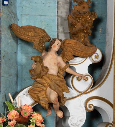 Zdjęcie nr 19: Kamienny ołtarz zamknięto w drewnianej obudowie, nakrywając go  drewnianą mensą z portatylem. Stipes ołtarzowy uzyskał kształt prostopadłościanu. Jego przód zdobi drewniane antepedium ujęte profilowaną ramą z malowanym chrystogramem "IHS" w glorii w polu. Na mensie ołtarza usytuowano tabernakulum w formie stojącego prostopadłościanu o wypukłym froncie i wklęsłych bokach wspierającego się na cokole. Jego przód ujmuje para kolumn podtrzymujących niepełne belkowanie, wyłamane nad ścianą frontową na kształt łuku odcinkowego nadwieszonego. Na froncie zamontowano obrotową, dwustronną niszę ujętą ramą w formie stojącego prostokąta zamkniętego łukiem półkolistym, wielolistnym. Nisze bębna zwieńczone zostały złoconymi konchami. Na tabernakulum usytuowano tron eucharystyczny w formie cokołu z leżącą księgą o siedmiu pieczęciach w glorii. Retabulum ołtarzowe wzniesiono na planie półowalu i polichromowano je na biało. Jest to architektoniczna, jednokondygnacyjna, jednoosiowa struktura ze zwieńczeniem. Po bokach flankują ją bramki ustawione na dwustrefowym, tralkowym, wklęsło-wypukłym cokole. Kondygnacja została ujęta dwiema parami pilastrów zwróconych delikatnie do wewnątrz oraz silnie wysuniętą do przodu parą kolumn o kapitelach kompozytowych. Podpory dźwigają pełne belkowanie o wklęsło-wypukłej linii. Nad polem środkowym belkowanie jest połączone gzymsem przyjmującym formę łuku falistego i wyłamane na osiach podpór. Kondygnacje ujmują spływy wolutowe połączone z łukowato wygiętymi wolutami podtrzymywanymi przez wysokie tralkowe cokoły, tworząc bramki ołtarza. W polu środkowym umieszczono obraz Zwiastowania ujęty profilowaną, złoconą ramą w formie stojącego prostokąta zamkniętego łukiem półkolistym nadwieszonym z uskokiem. Zwieńczenie uzyskało formę leżącego prostokąta flankowanego parą pilastrów zwróconych do wewnątrz oraz parą pilastrów zwróconych na zewnątrz, których trzony przechodzą w spływy wolutowe opadające na belkowanie. Pilastry dźwigają niepełne, wklęsło-wypukłe belkowanie przyjmujące nad polem formę łuku falistego. Całość wieńczy kartusz rokokowy z chrystogramem "IHS". W polu zwieńczenia znalazł się obraz św. Andrzeja w profilowanej, złoconej ramie o fantazyjnej formie zbliżonej do stojącego prostokąta. Pilastry kondygnacji ozdobiono kapitelami z rocaille'ów, a ich trzony udekorowano złoconymi, rokokowymi panneau ze zwisami utworzonymi z rocaille'ów, rozet i liści. Na ich tle usytuowano figury świętego króla i św. Jana Chrzciciela. Rzeźby stoją na górnej strefie cokołu na wspornikach z rocaille. Na ramie obrazu w polu środkowym, w przyłuczach i na belkowaniu znalazły się ornamenty roślinne. Z kolei na wolutowych łukach bramek umieszczono rokokowe wazony oraz pary figur aniołów z kartuszami. Na belkowaniu i wolutach zwieńczenia znajdują się dwie pary puttów. Także trzony pilastrów zwieńczenia dekorowane są złoconymi zwisami z rocaille'ów i kwiatów. Pole wokół obrazu św. Andrzeja zostało ozdobione fragmentami rocaille'ów. Pod gzymsem koronującym powyżej obrazu, podwieszono lambrekin, zdobiony przy górnej krawędzi złoconymi liśćmi i rocaille'm. 