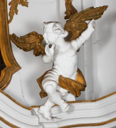 Zdjęcie nr 6: Kamienny ołtarz zamknięto w drewnianej obudowie, nakrywając go  drewnianą mensą z portatylem. Stipes ołtarzowy uzyskał kształt prostopadłościanu. Jego przód zdobi drewniane antepedium ujęte profilowaną ramą z malowanym chrystogramem "IHS" w glorii w polu. Na mensie ołtarza usytuowano tabernakulum w formie stojącego prostopadłościanu o wypukłym froncie i wklęsłych bokach wspierającego się na cokole. Jego przód ujmuje para kolumn podtrzymujących niepełne belkowanie, wyłamane nad ścianą frontową na kształt łuku odcinkowego nadwieszonego. Na froncie zamontowano obrotową, dwustronną niszę ujętą ramą w formie stojącego prostokąta zamkniętego łukiem półkolistym, wielolistnym. Nisze bębna zwieńczone zostały złoconymi konchami. Na tabernakulum usytuowano tron eucharystyczny w formie cokołu z leżącą księgą o siedmiu pieczęciach w glorii. Retabulum ołtarzowe wzniesiono na planie półowalu i polichromowano je na biało. Jest to architektoniczna, jednokondygnacyjna, jednoosiowa struktura ze zwieńczeniem. Po bokach flankują ją bramki ustawione na dwustrefowym, tralkowym, wklęsło-wypukłym cokole. Kondygnacja została ujęta dwiema parami pilastrów zwróconych delikatnie do wewnątrz oraz silnie wysuniętą do przodu parą kolumn o kapitelach kompozytowych. Podpory dźwigają pełne belkowanie o wklęsło-wypukłej linii. Nad polem środkowym belkowanie jest połączone gzymsem przyjmującym formę łuku falistego i wyłamane na osiach podpór. Kondygnacje ujmują spływy wolutowe połączone z łukowato wygiętymi wolutami podtrzymywanymi przez wysokie tralkowe cokoły, tworząc bramki ołtarza. W polu środkowym umieszczono obraz Zwiastowania ujęty profilowaną, złoconą ramą w formie stojącego prostokąta zamkniętego łukiem półkolistym nadwieszonym z uskokiem. Zwieńczenie uzyskało formę leżącego prostokąta flankowanego parą pilastrów zwróconych do wewnątrz oraz parą pilastrów zwróconych na zewnątrz, których trzony przechodzą w spływy wolutowe opadające na belkowanie. Pilastry dźwigają niepełne, wklęsło-wypukłe belkowanie przyjmujące nad polem formę łuku falistego. Całość wieńczy kartusz rokokowy z chrystogramem "IHS". W polu zwieńczenia znalazł się obraz św. Andrzeja w profilowanej, złoconej ramie o fantazyjnej formie zbliżonej do stojącego prostokąta. Pilastry kondygnacji ozdobiono kapitelami z rocaille'ów, a ich trzony udekorowano złoconymi, rokokowymi panneau ze zwisami utworzonymi z rocaille'ów, rozet i liści. Na ich tle usytuowano figury świętego króla i św. Jana Chrzciciela. Rzeźby stoją na górnej strefie cokołu na wspornikach z rocaille. Na ramie obrazu w polu środkowym, w przyłuczach i na belkowaniu znalazły się ornamenty roślinne. Z kolei na wolutowych łukach bramek umieszczono rokokowe wazony oraz pary figur aniołów z kartuszami. Na belkowaniu i wolutach zwieńczenia znajdują się dwie pary puttów. Także trzony pilastrów zwieńczenia dekorowane są złoconymi zwisami z rocaille'ów i kwiatów. Pole wokół obrazu św. Andrzeja zostało ozdobione fragmentami rocaille'ów. Pod gzymsem koronującym powyżej obrazu, podwieszono lambrekin, zdobiony przy górnej krawędzi złoconymi liśćmi i rocaille'm. 