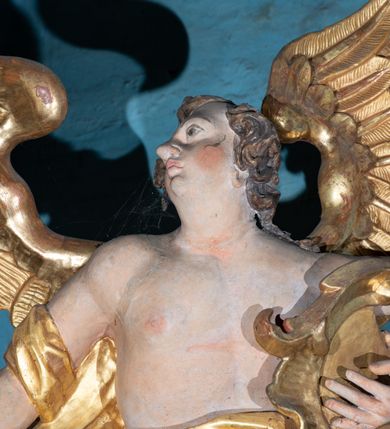 Zdjęcie nr 11: Kamienny ołtarz zamknięto w drewnianej obudowie, nakrywając go  drewnianą mensą z portatylem. Stipes ołtarzowy uzyskał kształt prostopadłościanu. Jego przód zdobi drewniane antepedium ujęte profilowaną ramą z malowanym chrystogramem "IHS" w glorii w polu. Na mensie ołtarza usytuowano tabernakulum w formie stojącego prostopadłościanu o wypukłym froncie i wklęsłych bokach wspierającego się na cokole. Jego przód ujmuje para kolumn podtrzymujących niepełne belkowanie, wyłamane nad ścianą frontową na kształt łuku odcinkowego nadwieszonego. Na froncie zamontowano obrotową, dwustronną niszę ujętą ramą w formie stojącego prostokąta zamkniętego łukiem półkolistym, wielolistnym. Nisze bębna zwieńczone zostały złoconymi konchami. Na tabernakulum usytuowano tron eucharystyczny w formie cokołu z leżącą księgą o siedmiu pieczęciach w glorii. Retabulum ołtarzowe wzniesiono na planie półowalu i polichromowano je na biało. Jest to architektoniczna, jednokondygnacyjna, jednoosiowa struktura ze zwieńczeniem. Po bokach flankują ją bramki ustawione na dwustrefowym, tralkowym, wklęsło-wypukłym cokole. Kondygnacja została ujęta dwiema parami pilastrów zwróconych delikatnie do wewnątrz oraz silnie wysuniętą do przodu parą kolumn o kapitelach kompozytowych. Podpory dźwigają pełne belkowanie o wklęsło-wypukłej linii. Nad polem środkowym belkowanie jest połączone gzymsem przyjmującym formę łuku falistego i wyłamane na osiach podpór. Kondygnacje ujmują spływy wolutowe połączone z łukowato wygiętymi wolutami podtrzymywanymi przez wysokie tralkowe cokoły, tworząc bramki ołtarza. W polu środkowym umieszczono obraz Zwiastowania ujęty profilowaną, złoconą ramą w formie stojącego prostokąta zamkniętego łukiem półkolistym nadwieszonym z uskokiem. Zwieńczenie uzyskało formę leżącego prostokąta flankowanego parą pilastrów zwróconych do wewnątrz oraz parą pilastrów zwróconych na zewnątrz, których trzony przechodzą w spływy wolutowe opadające na belkowanie. Pilastry dźwigają niepełne, wklęsło-wypukłe belkowanie przyjmujące nad polem formę łuku falistego. Całość wieńczy kartusz rokokowy z chrystogramem "IHS". W polu zwieńczenia znalazł się obraz św. Andrzeja w profilowanej, złoconej ramie o fantazyjnej formie zbliżonej do stojącego prostokąta. Pilastry kondygnacji ozdobiono kapitelami z rocaille'ów, a ich trzony udekorowano złoconymi, rokokowymi panneau ze zwisami utworzonymi z rocaille'ów, rozet i liści. Na ich tle usytuowano figury świętego króla i św. Jana Chrzciciela. Rzeźby stoją na górnej strefie cokołu na wspornikach z rocaille. Na ramie obrazu w polu środkowym, w przyłuczach i na belkowaniu znalazły się ornamenty roślinne. Z kolei na wolutowych łukach bramek umieszczono rokokowe wazony oraz pary figur aniołów z kartuszami. Na belkowaniu i wolutach zwieńczenia znajdują się dwie pary puttów. Także trzony pilastrów zwieńczenia dekorowane są złoconymi zwisami z rocaille'ów i kwiatów. Pole wokół obrazu św. Andrzeja zostało ozdobione fragmentami rocaille'ów. Pod gzymsem koronującym powyżej obrazu, podwieszono lambrekin, zdobiony przy górnej krawędzi złoconymi liśćmi i rocaille'm. 