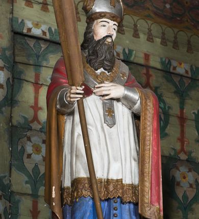 Zdjęcie nr 11: Nastawa ołtarzowa na planie półowalu uzyskała architektoniczną, jednokondygnacyjną strukturę ze zwieńczeniem. Jednoosiowe retabulum flankowane bramkami, na których ustawiono figury św. Wojciecha i św. Stanisława. Stipes ołtarz ujmuje drewniana prostopadłościenna obudowa podtrzymująca drewnianą mensą z portatylem. Drewniane antependium ujęte zostało czworoboczną, profilowaną ramą z płaskorzeźbionym i złoconym barankiem apokaliptycznym leżącym na księdze. Na mensie ustawiono współczesne tabernakulum pancerne w formie prostopadłościennej skrzynki. Kondygnacja retabulum ujęta została dwiema parami pilastrów zwróconych delikatnie do wewnątrz oraz silnie wysuniętą do przodu parą kolumn o kapitelach kompozytowych oraz dwie wolutowe konsole. Podpory dźwigają pełne belkowanie wsparte na impostach, o wklęsło-wypukłej linii. Nad polem środkowym widoczne jest połączenie wyłącznie gzymsem przyjmującym formę łuku falistego, wyłamane na osiach podpór. Na środku belkowania umieszczono kartusz, od którego odchodzą dwie girland kwiatowe. Kondygnacje ujmują zredukowane do wici akantowej uszaki. W polu środkowym usytuowano obraz św. Wawrzyńca ujęty profilowaną ramą w formie stojącego prostokąta zamkniętego łukiem nadwieszonym. Zwieńczenie nastawy uzyskało formę leżącego prostokąta flankowanego dwoma spływami wolutowymi opadającymi na belkowanie. Obie woluty dźwigają niepełne, wklęsło-wypukłe belkowanie przyjmujące nad polem formę łuku falistego. W centrum zwieńczenia umieszczono rzeźbioną grupę ze sceną koronacji Marii w srebrzonych obłokach z promieniami. Struktura nastawy jest polichromowana w kolorze białym, kolumny, konsole, profile i ornamentyka pierwotnie były złocone.