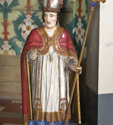 Zdjęcie nr 13: Nastawa ołtarzowa na planie półowalu uzyskała architektoniczną, jednokondygnacyjną strukturę ze zwieńczeniem. Jednoosiowe retabulum flankowane bramkami, na których ustawiono figury św. Wojciecha i św. Stanisława. Stipes ołtarz ujmuje drewniana prostopadłościenna obudowa podtrzymująca drewnianą mensą z portatylem. Drewniane antependium ujęte zostało czworoboczną, profilowaną ramą z płaskorzeźbionym i złoconym barankiem apokaliptycznym leżącym na księdze. Na mensie ustawiono współczesne tabernakulum pancerne w formie prostopadłościennej skrzynki. Kondygnacja retabulum ujęta została dwiema parami pilastrów zwróconych delikatnie do wewnątrz oraz silnie wysuniętą do przodu parą kolumn o kapitelach kompozytowych oraz dwie wolutowe konsole. Podpory dźwigają pełne belkowanie wsparte na impostach, o wklęsło-wypukłej linii. Nad polem środkowym widoczne jest połączenie wyłącznie gzymsem przyjmującym formę łuku falistego, wyłamane na osiach podpór. Na środku belkowania umieszczono kartusz, od którego odchodzą dwie girland kwiatowe. Kondygnacje ujmują zredukowane do wici akantowej uszaki. W polu środkowym usytuowano obraz św. Wawrzyńca ujęty profilowaną ramą w formie stojącego prostokąta zamkniętego łukiem nadwieszonym. Zwieńczenie nastawy uzyskało formę leżącego prostokąta flankowanego dwoma spływami wolutowymi opadającymi na belkowanie. Obie woluty dźwigają niepełne, wklęsło-wypukłe belkowanie przyjmujące nad polem formę łuku falistego. W centrum zwieńczenia umieszczono rzeźbioną grupę ze sceną koronacji Marii w srebrzonych obłokach z promieniami. Struktura nastawy jest polichromowana w kolorze białym, kolumny, konsole, profile i ornamentyka pierwotnie były złocone.