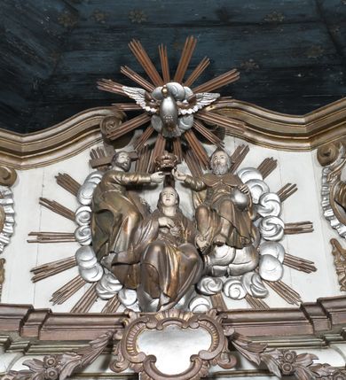Zdjęcie nr 9: Nastawa ołtarzowa na planie półowalu uzyskała architektoniczną, jednokondygnacyjną strukturę ze zwieńczeniem. Jednoosiowe retabulum flankowane bramkami, na których ustawiono figury św. Wojciecha i św. Stanisława. Stipes ołtarz ujmuje drewniana prostopadłościenna obudowa podtrzymująca drewnianą mensą z portatylem. Drewniane antependium ujęte zostało czworoboczną, profilowaną ramą z płaskorzeźbionym i złoconym barankiem apokaliptycznym leżącym na księdze. Na mensie ustawiono współczesne tabernakulum pancerne w formie prostopadłościennej skrzynki. Kondygnacja retabulum ujęta została dwiema parami pilastrów zwróconych delikatnie do wewnątrz oraz silnie wysuniętą do przodu parą kolumn o kapitelach kompozytowych oraz dwie wolutowe konsole. Podpory dźwigają pełne belkowanie wsparte na impostach, o wklęsło-wypukłej linii. Nad polem środkowym widoczne jest połączenie wyłącznie gzymsem przyjmującym formę łuku falistego, wyłamane na osiach podpór. Na środku belkowania umieszczono kartusz, od którego odchodzą dwie girland kwiatowe. Kondygnacje ujmują zredukowane do wici akantowej uszaki. W polu środkowym usytuowano obraz św. Wawrzyńca ujęty profilowaną ramą w formie stojącego prostokąta zamkniętego łukiem nadwieszonym. Zwieńczenie nastawy uzyskało formę leżącego prostokąta flankowanego dwoma spływami wolutowymi opadającymi na belkowanie. Obie woluty dźwigają niepełne, wklęsło-wypukłe belkowanie przyjmujące nad polem formę łuku falistego. W centrum zwieńczenia umieszczono rzeźbioną grupę ze sceną koronacji Marii w srebrzonych obłokach z promieniami. Struktura nastawy jest polichromowana w kolorze białym, kolumny, konsole, profile i ornamentyka pierwotnie były złocone.
