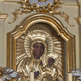 Zdjęcie nr 1: Obraz w formie stojącego prostokąta. Twarz i dłonie odsłonięte, malowane, pozostała część obrazu przykryta płaskorzeźbioną, złoconą sukienką. W centrum Matka Boska w półpostaci, zwrócona frontalnie, na lewym przedramieniu podtrzymuje Dzieciątko, prawą ręką wskazuje na nie. Twarz owalna o wyrazistych rysach i ciemnej karnacji. Dzieciątko siedzi zwrócone w trzech czwartych w prawo, lewą ręką trzyma na kolanach księgę, prawą unosi w geście błogosławieństwa. Na głowach korony, wokół głów nimby, wokół postaci gloria promienista. W dolnej części obrazu znajduje się złocona szarfa z napisem „POD TWOJĄ OBRONĘ”.