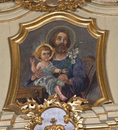 Zdjęcie nr 9: Nastawa ołtarzowa jest architektoniczna, jednoosiowa, jednokondygnacyjna ze zwieńczeniem, ustawiona na wysokim cokole. Ołtarz jest murowany, prostopadłościenny z marmurową mensą z portatylem. Trzy boki ołtarza ujmują malowane na płótnie obrazy w profilowanych, polichromowanych ramach. W polu antepedium znajduje się wyobrażenie architektonicznej nastawy z przedstawieniem baranka na ołtarzu, którą flankują sylwetki św. Piotra i św. Pawła.Tabernakulum ołtarza w formie metalowej skrzynki o wypukłym froncie i drewnianej obudowie w postaci wklęsłych boków zamkniętych parą pilastrów, których trzony przechodzą w spływy wolutowe. Podpory dźwigają profilowany gzyms przebiegający przez całą szerokość tabernakulum, nad frontem dekorowany lambrekinem. Metalowe drzwiczki mają kształt stojącego prostokąta zamkniętego łukiem półkolistym z aplikacjami w postaci kielicha z hostią w glorii, kłosami zbóż i winnego grona. Ponad drzwiczkami znajduje się kartusz z przedstawieniem pelikana. Na tabernakulum umiejscowiony jest tron wystawienia  w formie rzeźbionego ornamentalnego tła, flankowany przez parę rzeźbionych aniołów trzymających lichtarze. Retabulum ujęte jest parą opilastrowanych filarów i parą stojących przed nimi kolumn o kapitelach kompozytowych ustawionych pod kątem względem lica ołtarza. Podpory dźwigają wyłamujące się ponad nimi belkowanie z przerwanymi nad polem środkowym architrawem i fryzem. Zwieńczenie flankuje para spływów wolutowych, zamyka fragment wyłamanego na końcach gzymsu. Retabulum ujmuje para ażurowych, rocaille'owych uszaków, a w zwieńczeniu para figur adorujących aniołów. Trzony pilastrów zdobią rocaille'owe zwisy. W polu środkowym retabulum jest wnęka w formie stojącego prostokąta zamkniętego uskokowym, nadwieszonym łukiem półkolistym, ujęta profilowaną ramą. Wewnątrz znajduje się obraz Matki Boskiej z Dzieciątkiem. Powyżej, pośrodku belkowania umieszczono rocaille'owy kartusz z płaskorzeźbioną, zamkniętą koroną w polu. W zwieńczeniu jest obraz św. Józefa w profilowanej ramie w kształcie zbliżonym do stojącego prostokąta zamkniętego łukiem segmentowym z uskokiem oraz wklęsłymi dolnymi narożami. Szczyt ma formę rokokowego kartusza z malowanym okiem Opatrzności. Na zdobionych motywami rocaille'owymi wolutach spływów znajduje się para aniołów. 

Struktura ołtarza jest polichromowana w kolorze beżowym, trzony kolumn marmoryzowane, ornamentyka i profile złocone. 
